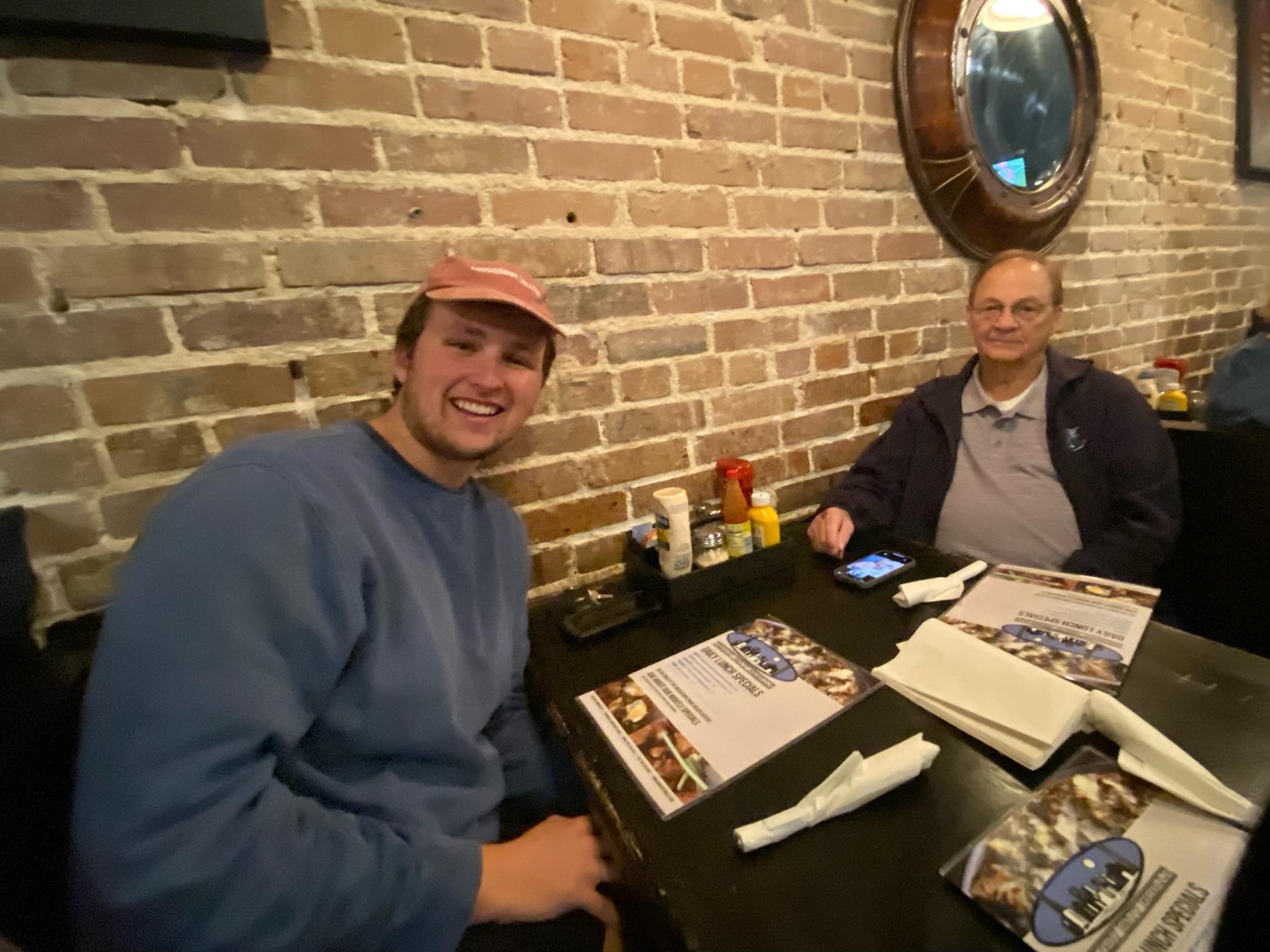 A man sitting at a table with a man in a hat