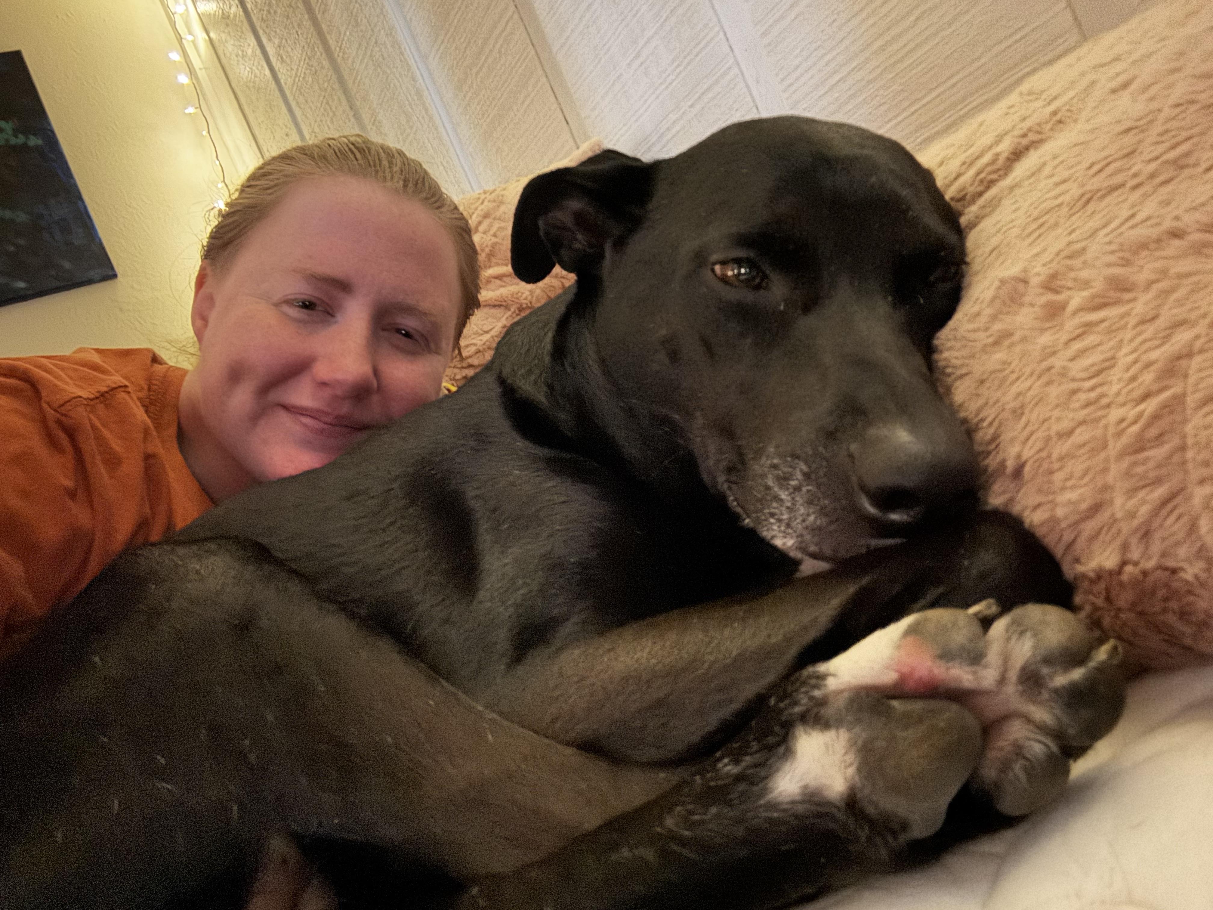 A woman lying on a couch with a dog