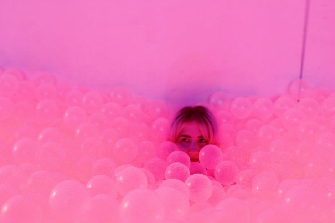 A woman hiding in a pile of balloons