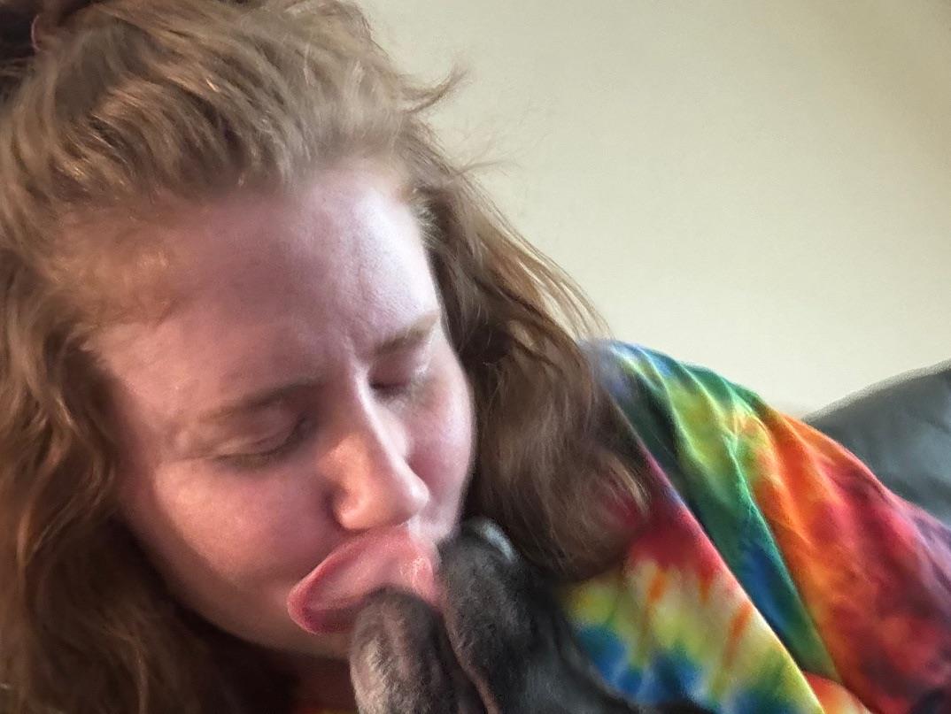 A woman licking a dog