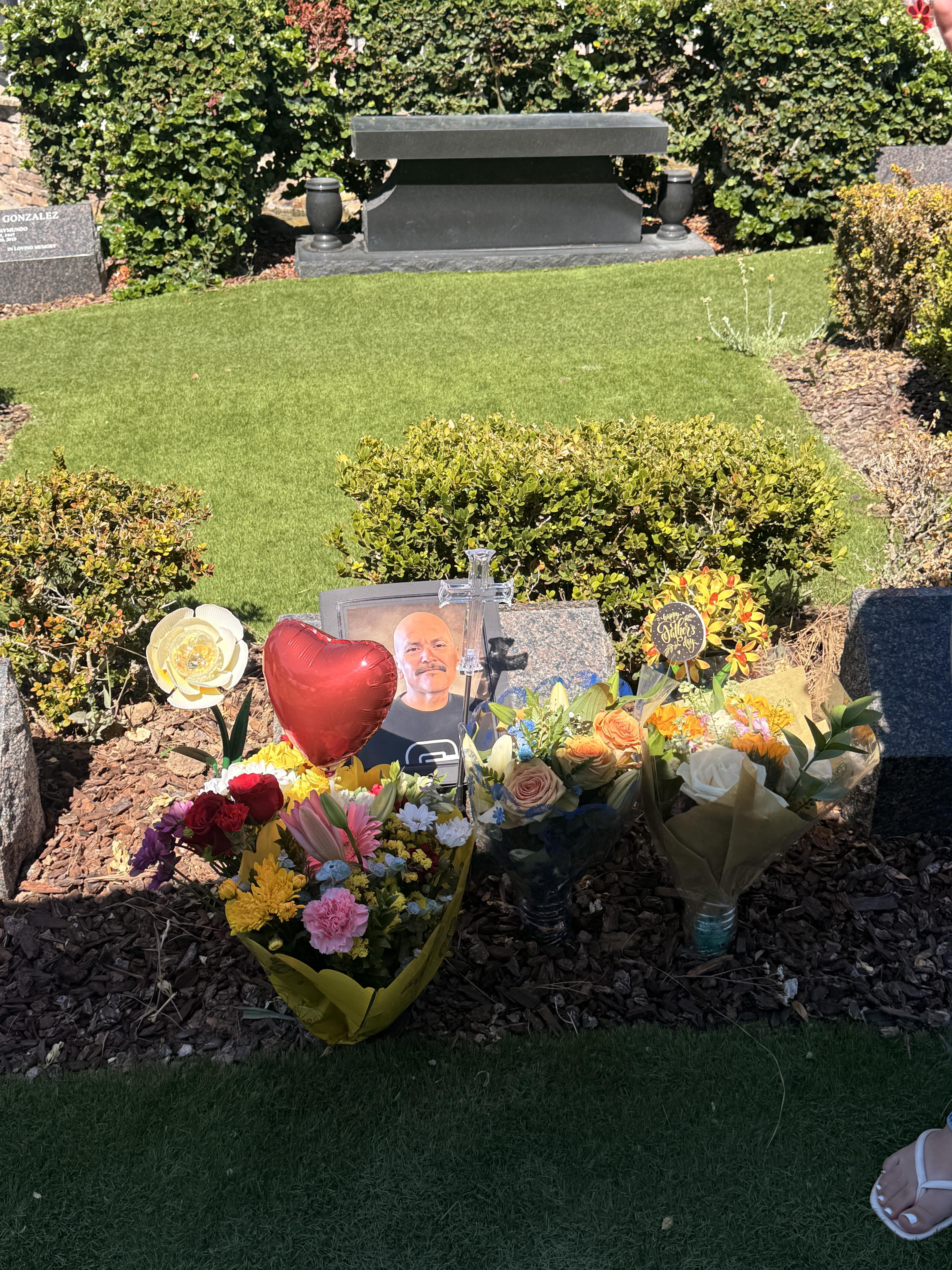 A grave with flowers and a picture of a man