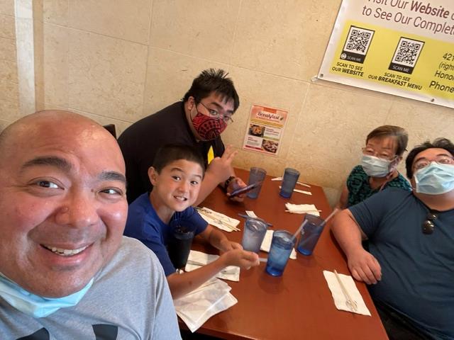 A group of people sitting at a table with face masks