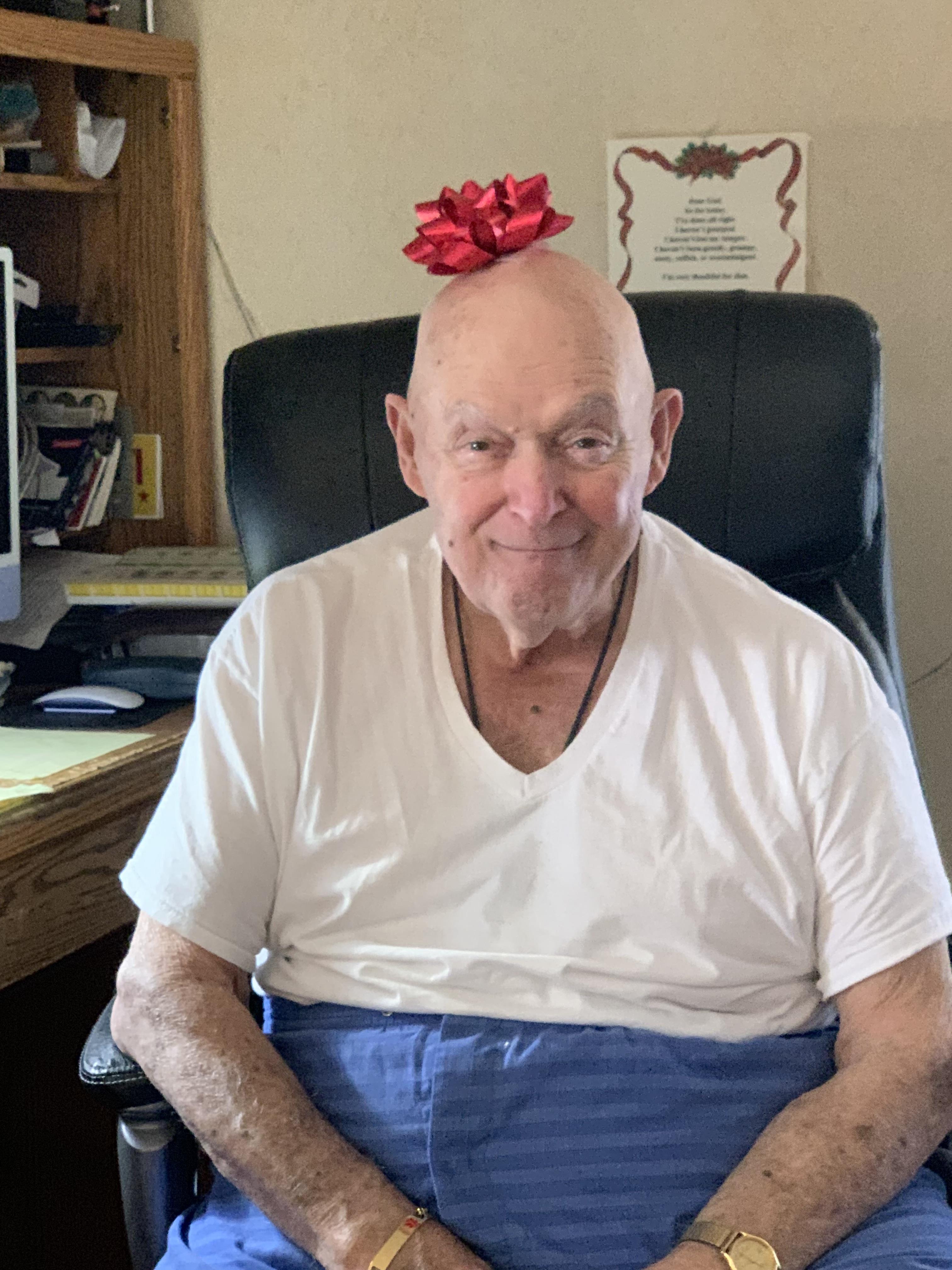 A man sitting in a chair with a red bow on his head