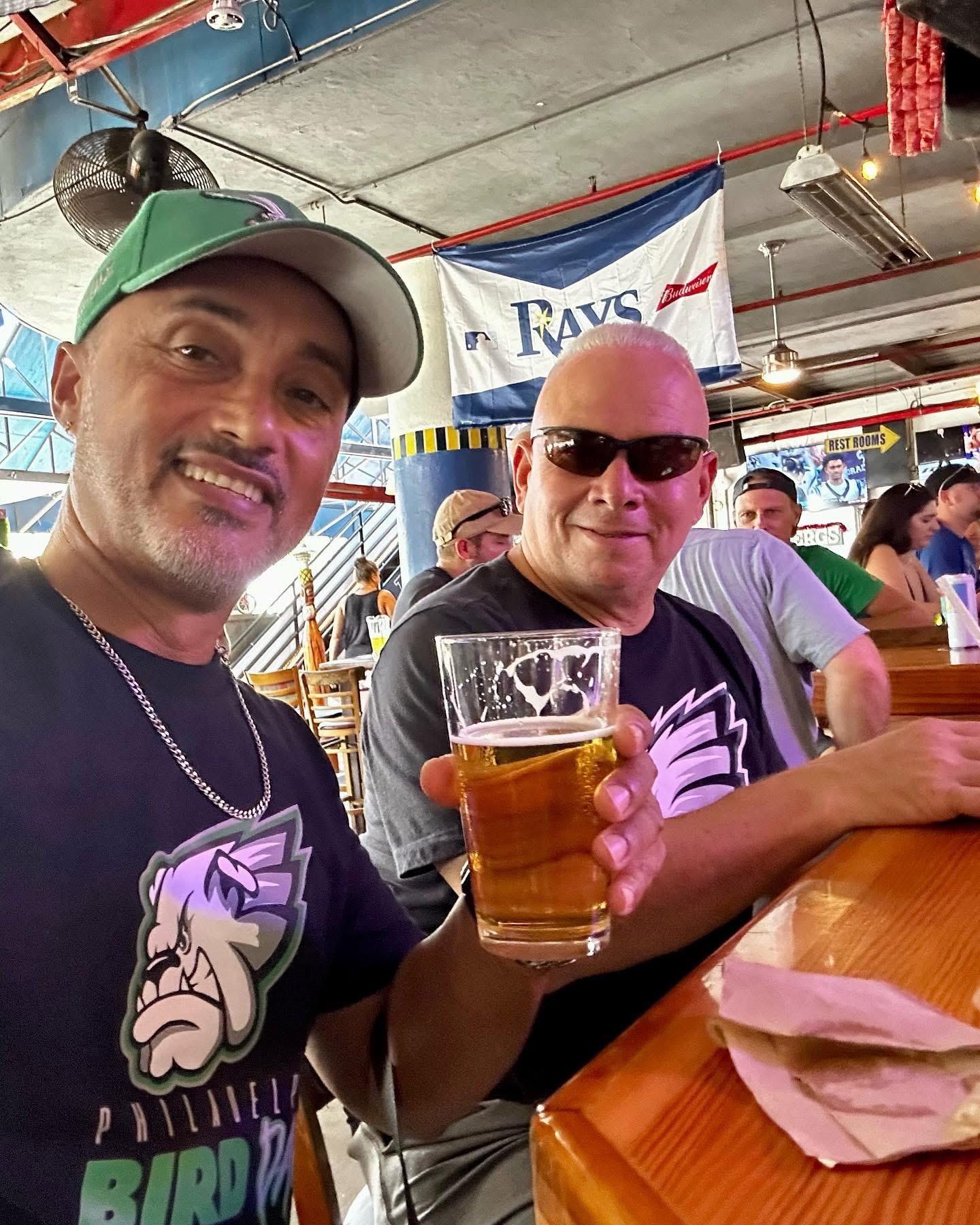 Two men sitting at a bar holding a glass of beer