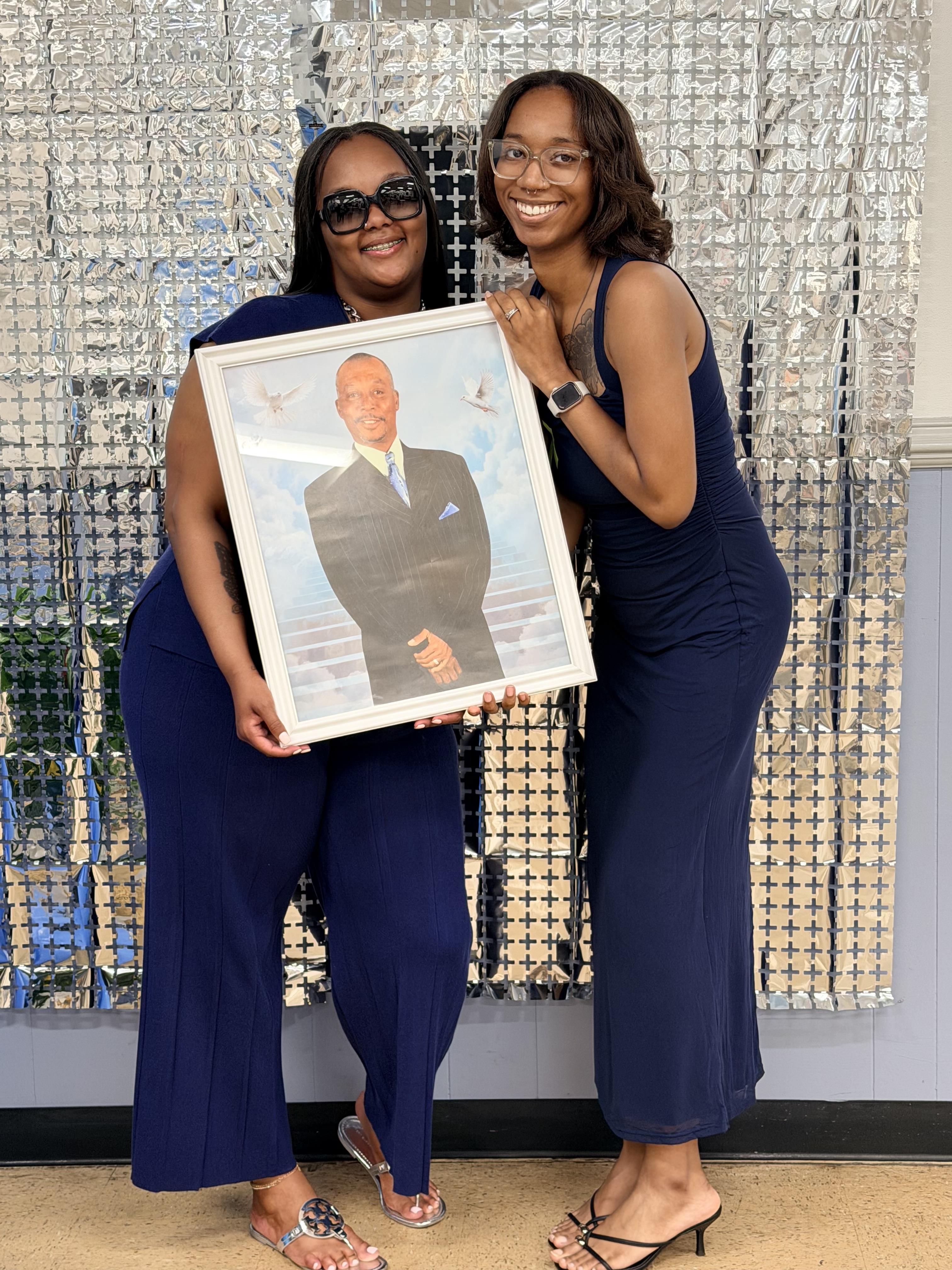 Two women holding a picture of a man