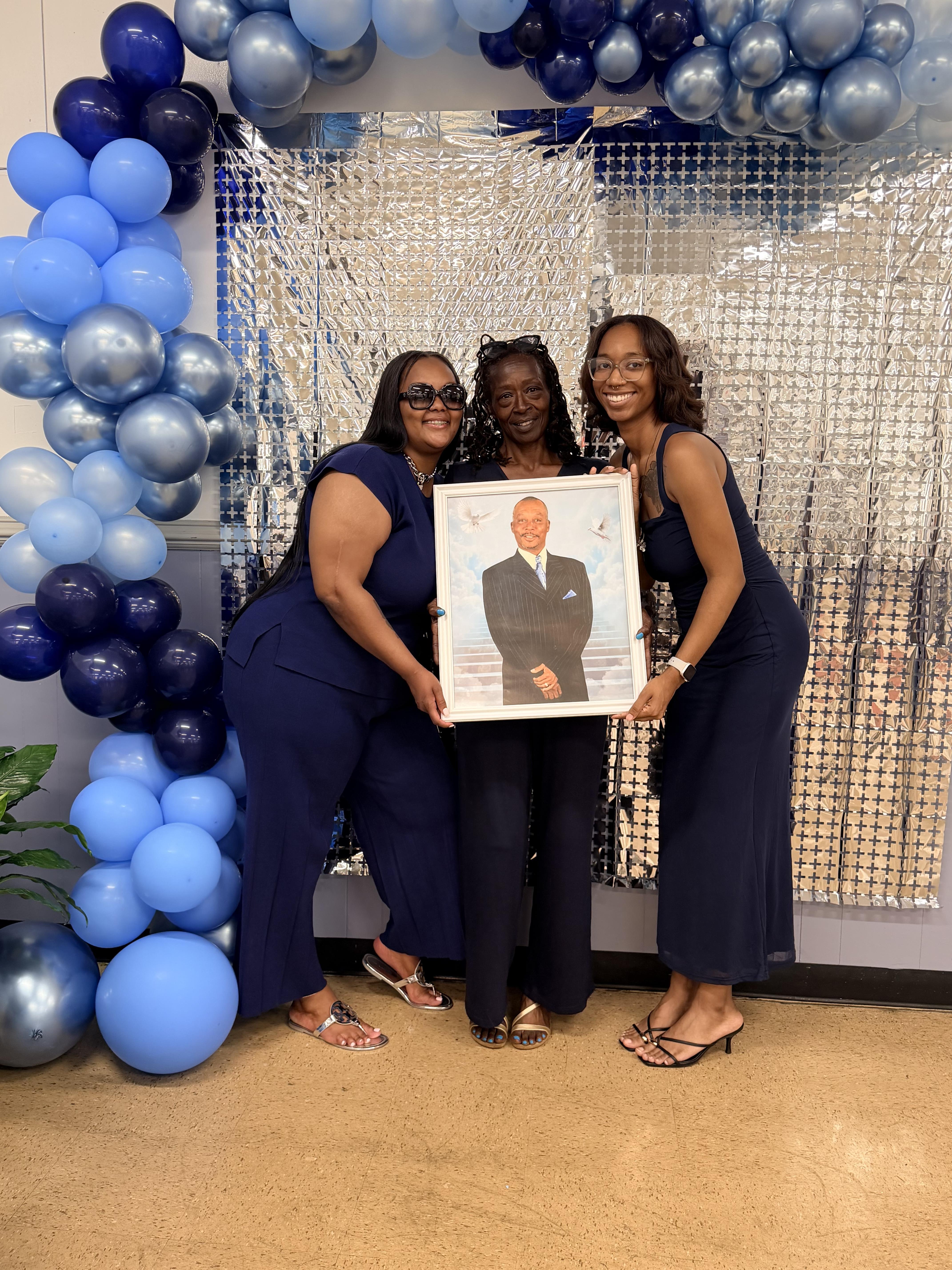 A group of women holding a picture of a man
