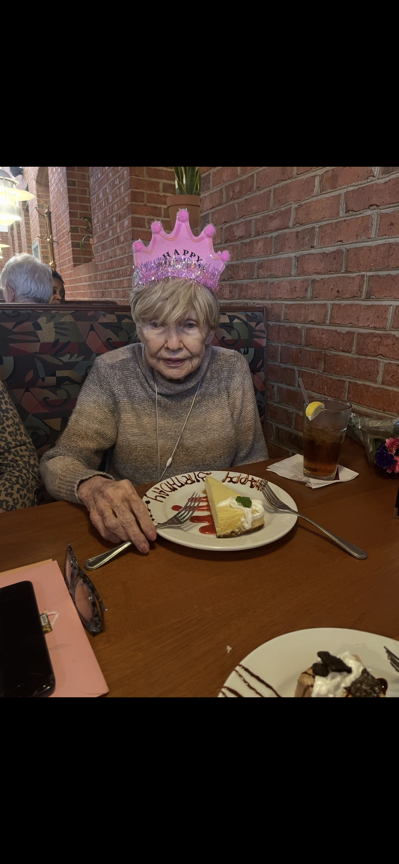 An old woman sitting at a table with a plate of cake