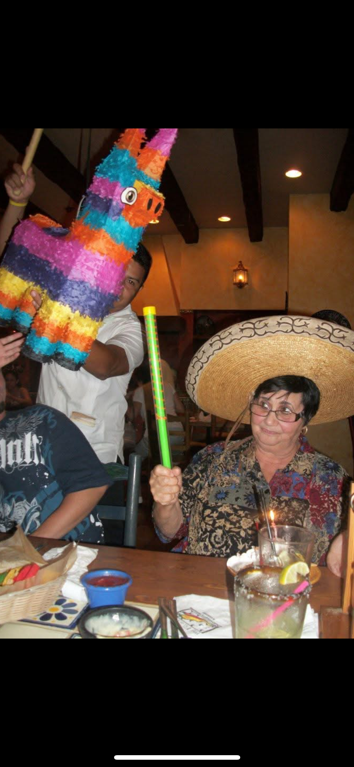 A woman wearing a sombrero holding a pinata
