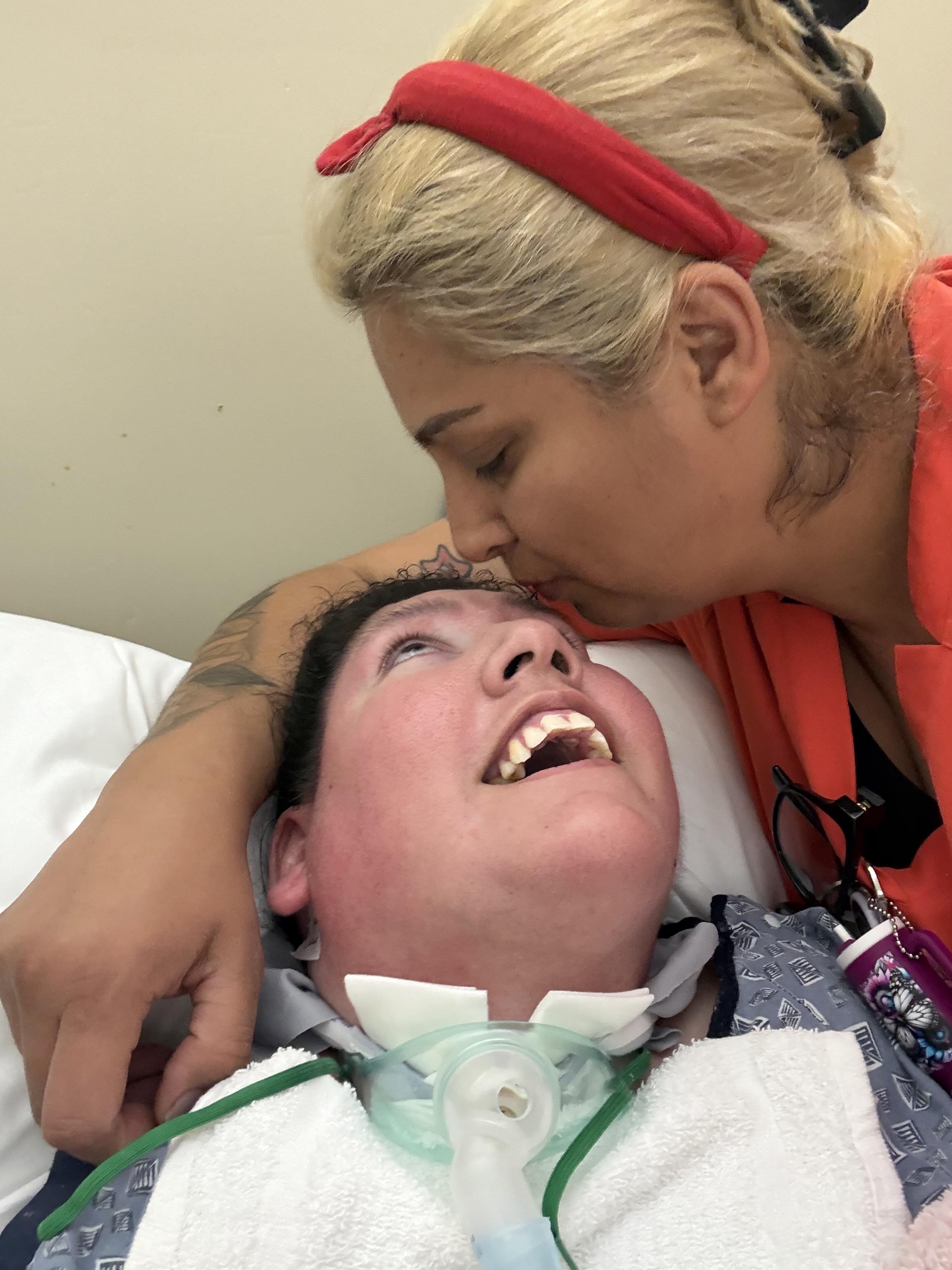 A woman kissing a man in a hospital bed
