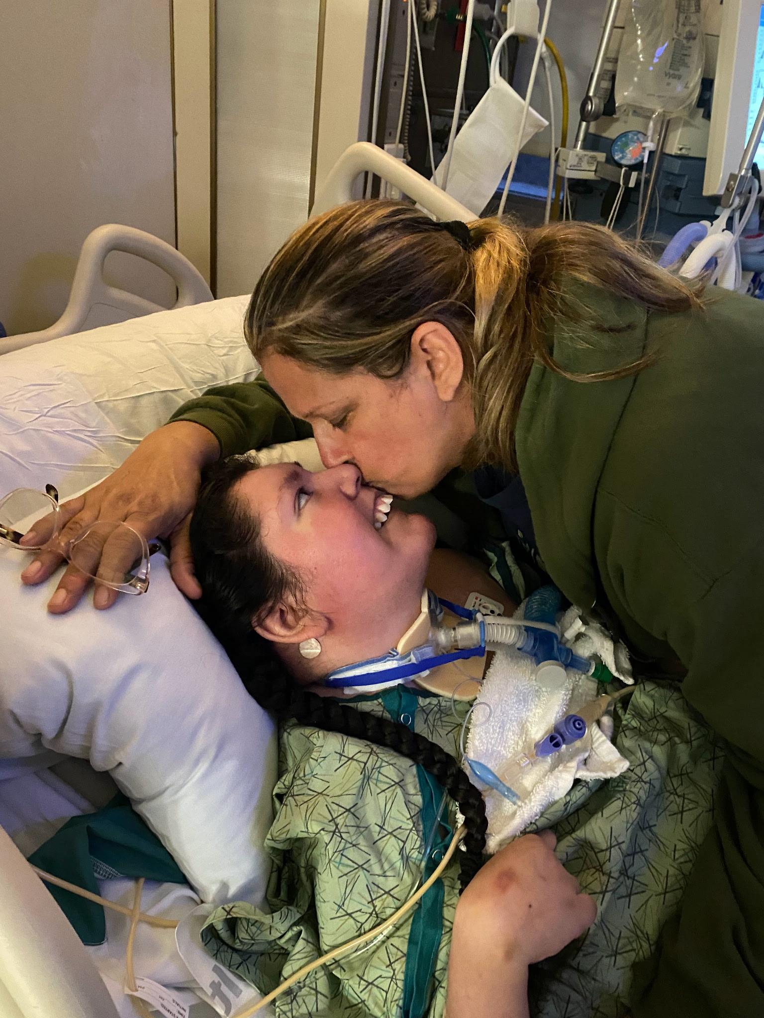A woman kissing a woman in a hospital bed