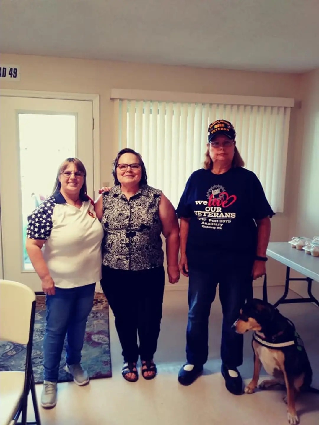 A group of women standing in a room with a dog