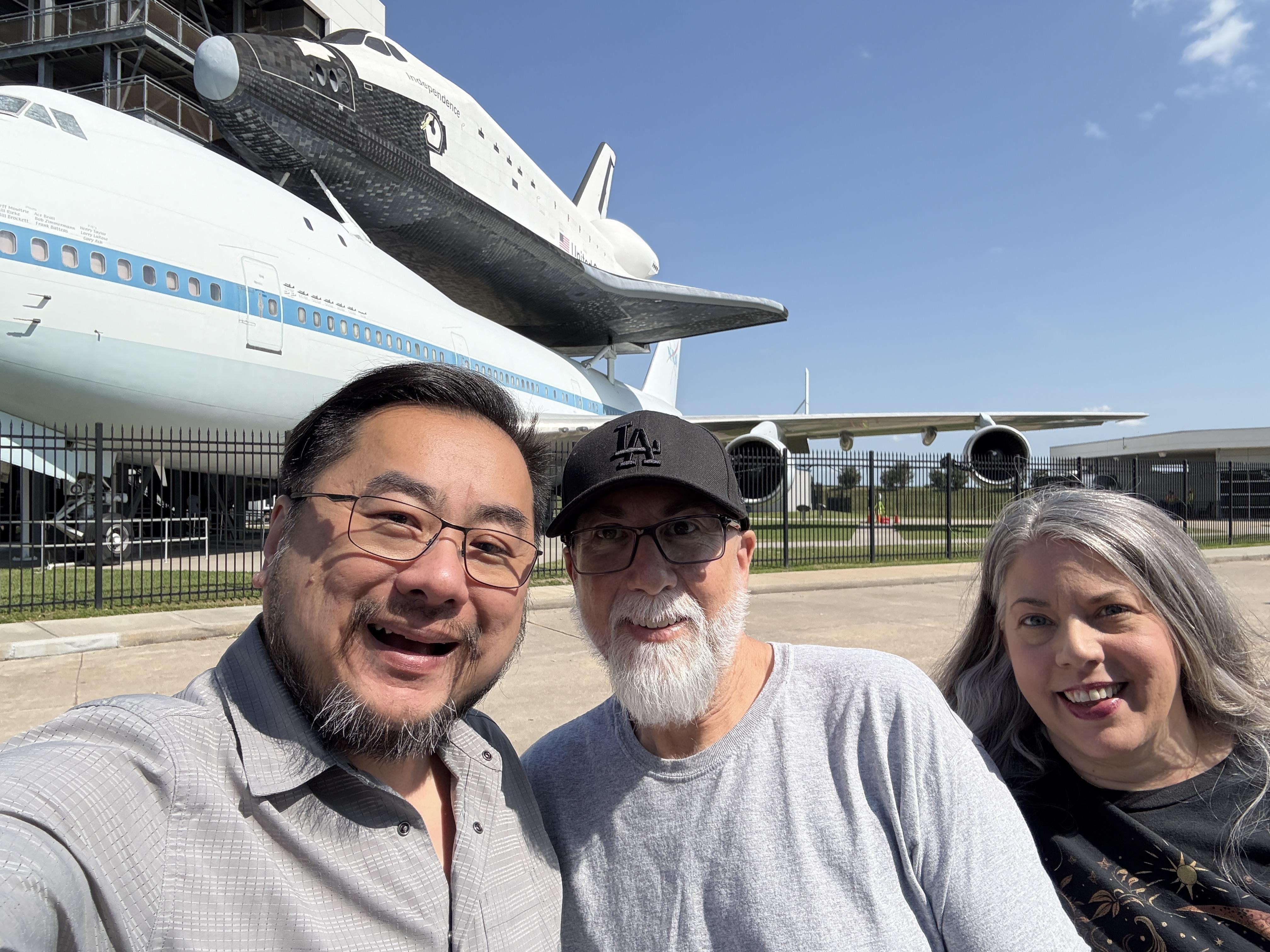 A group of people taking a selfie in front of a space shuttle