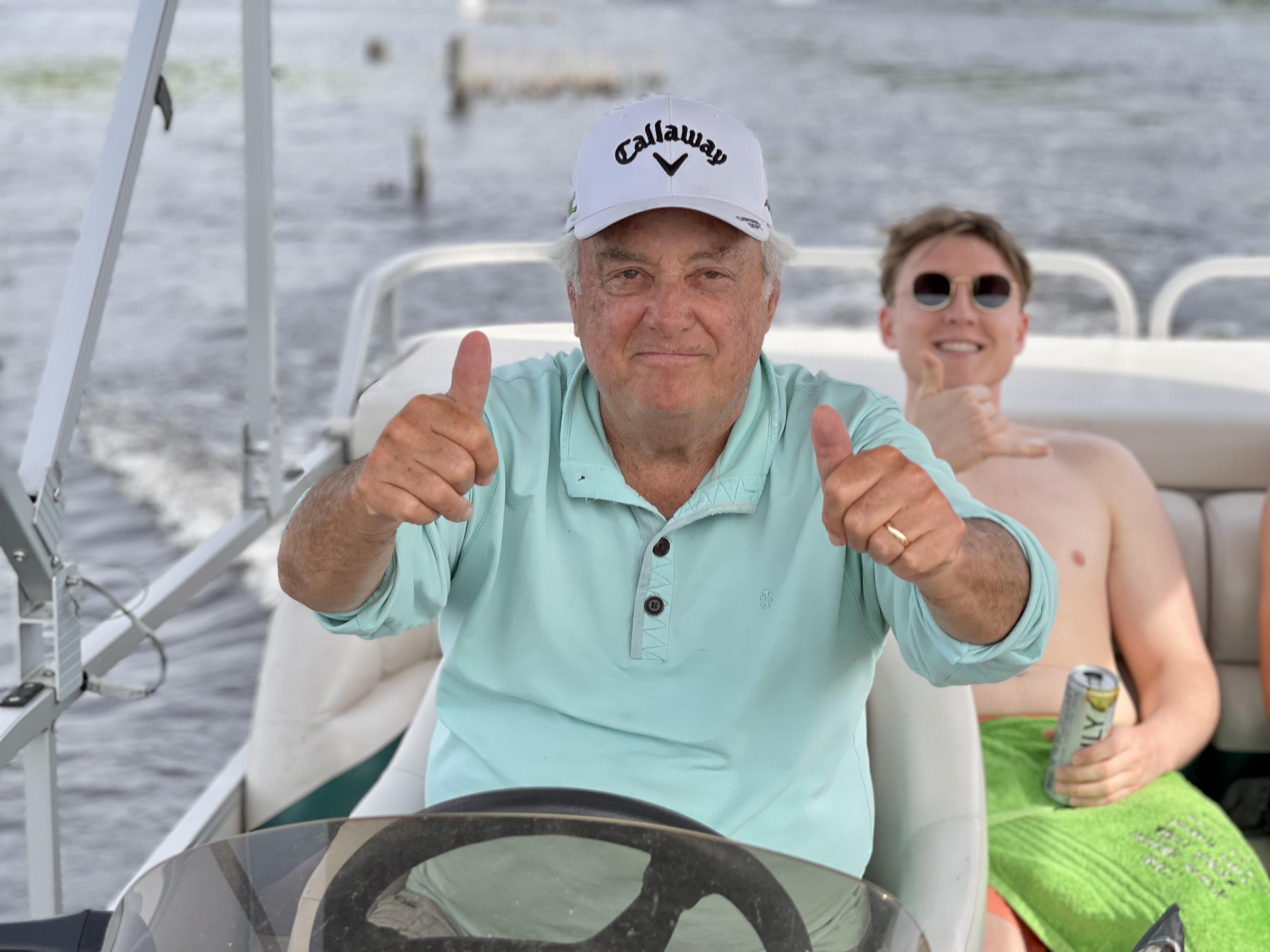 A man in a white hat giving thumbs up with a woman in a boat