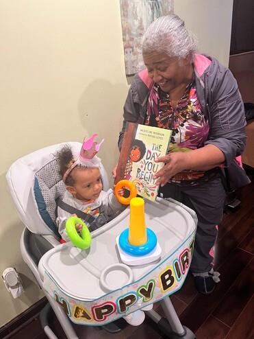 A woman holding a book to a baby