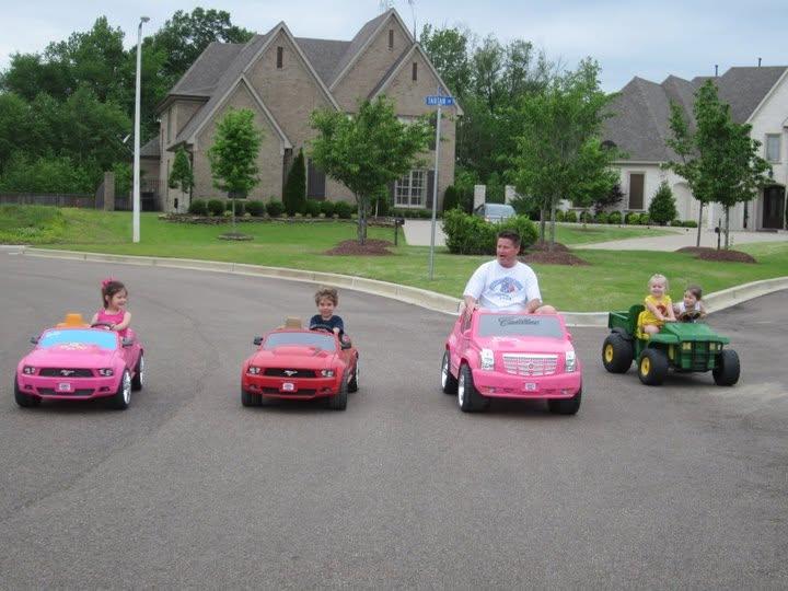 A man driving a toy car with kids