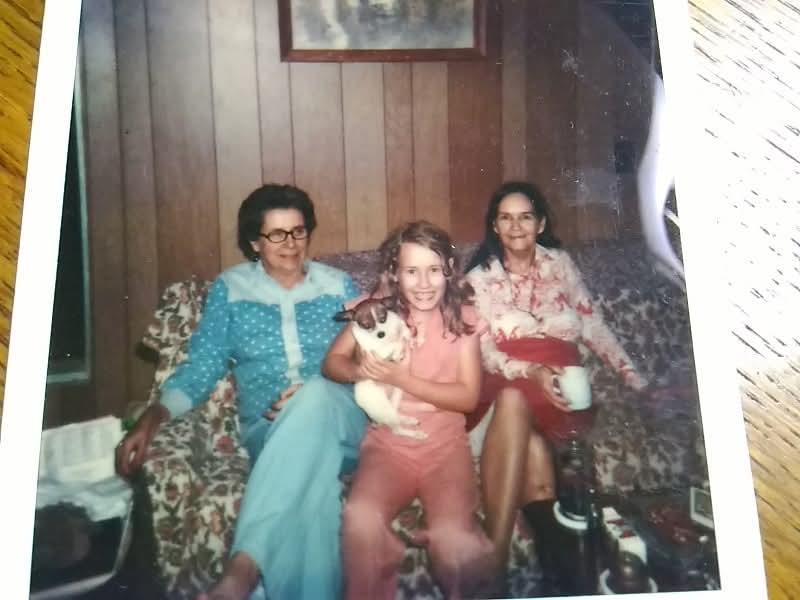 A group of women sitting on a couch with a dog