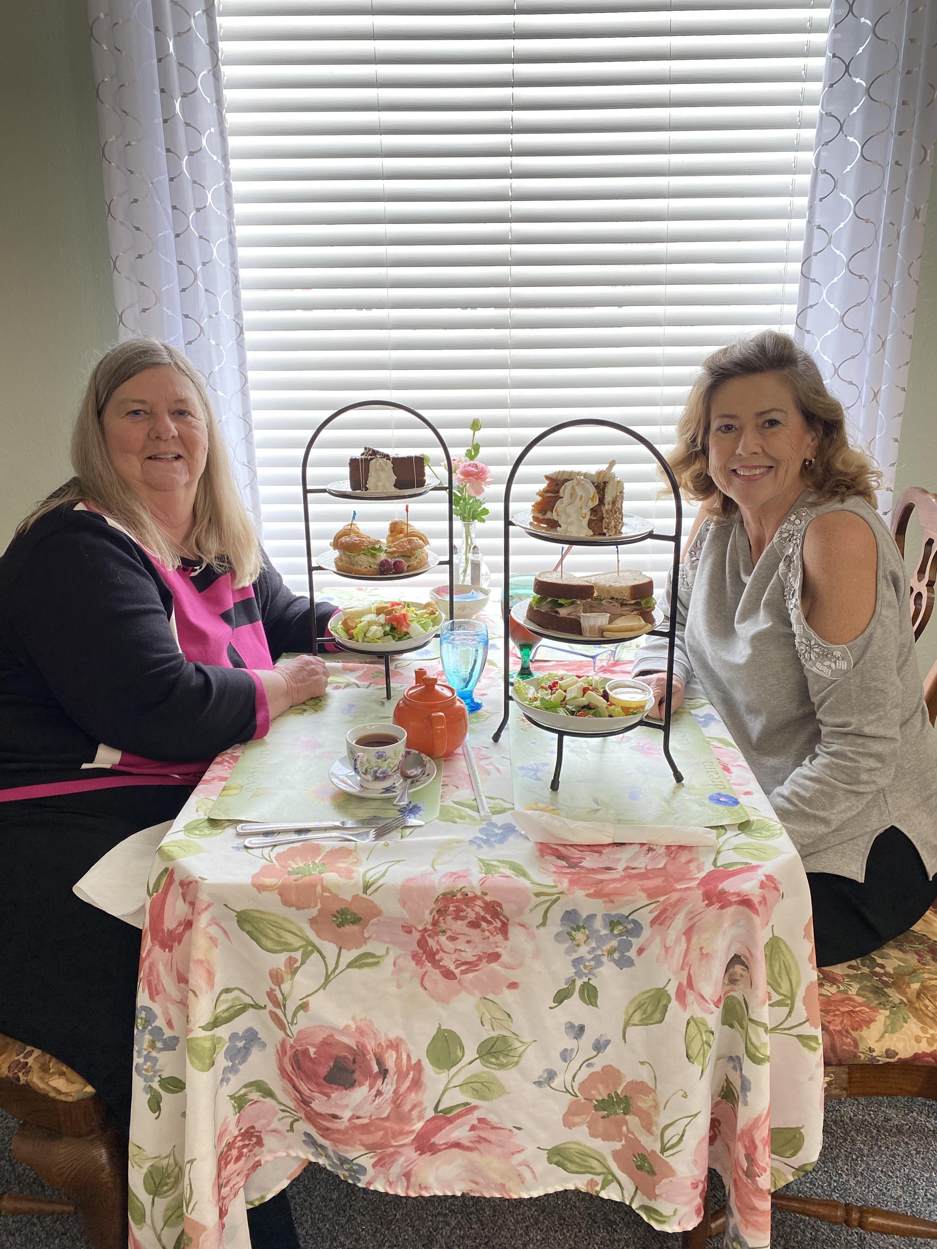 Two women sitting at a table with food on it