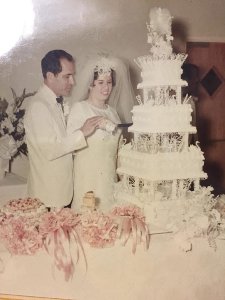 A man and woman standing next to a wedding cake
