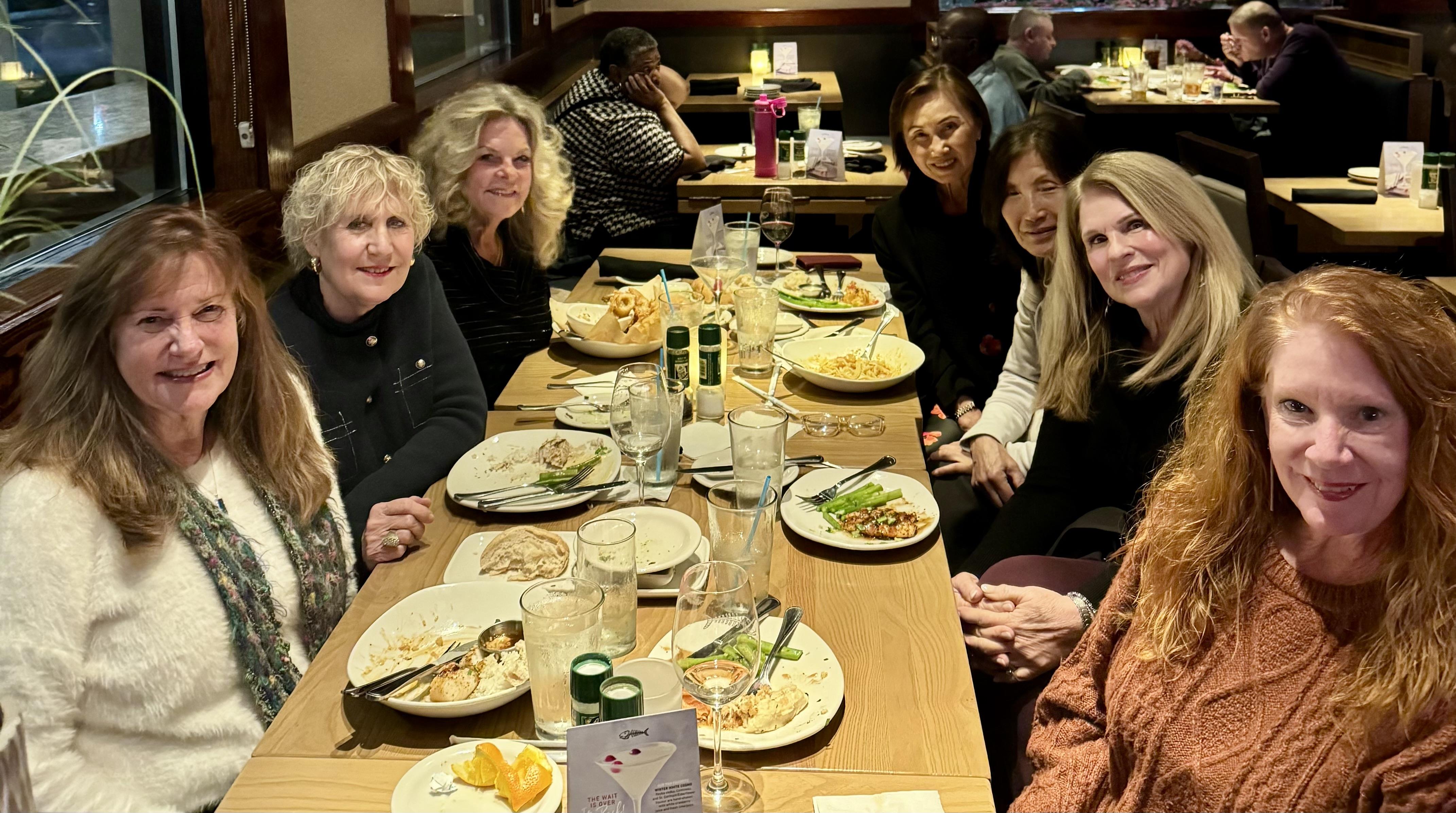 A group of women sitting at a long table with plates of food