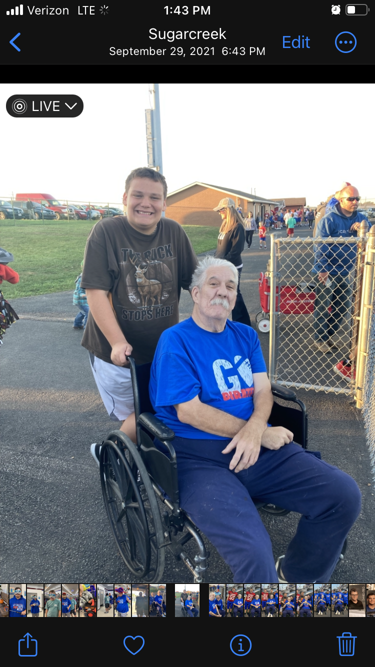 A man in a wheelchair with a boy behind him