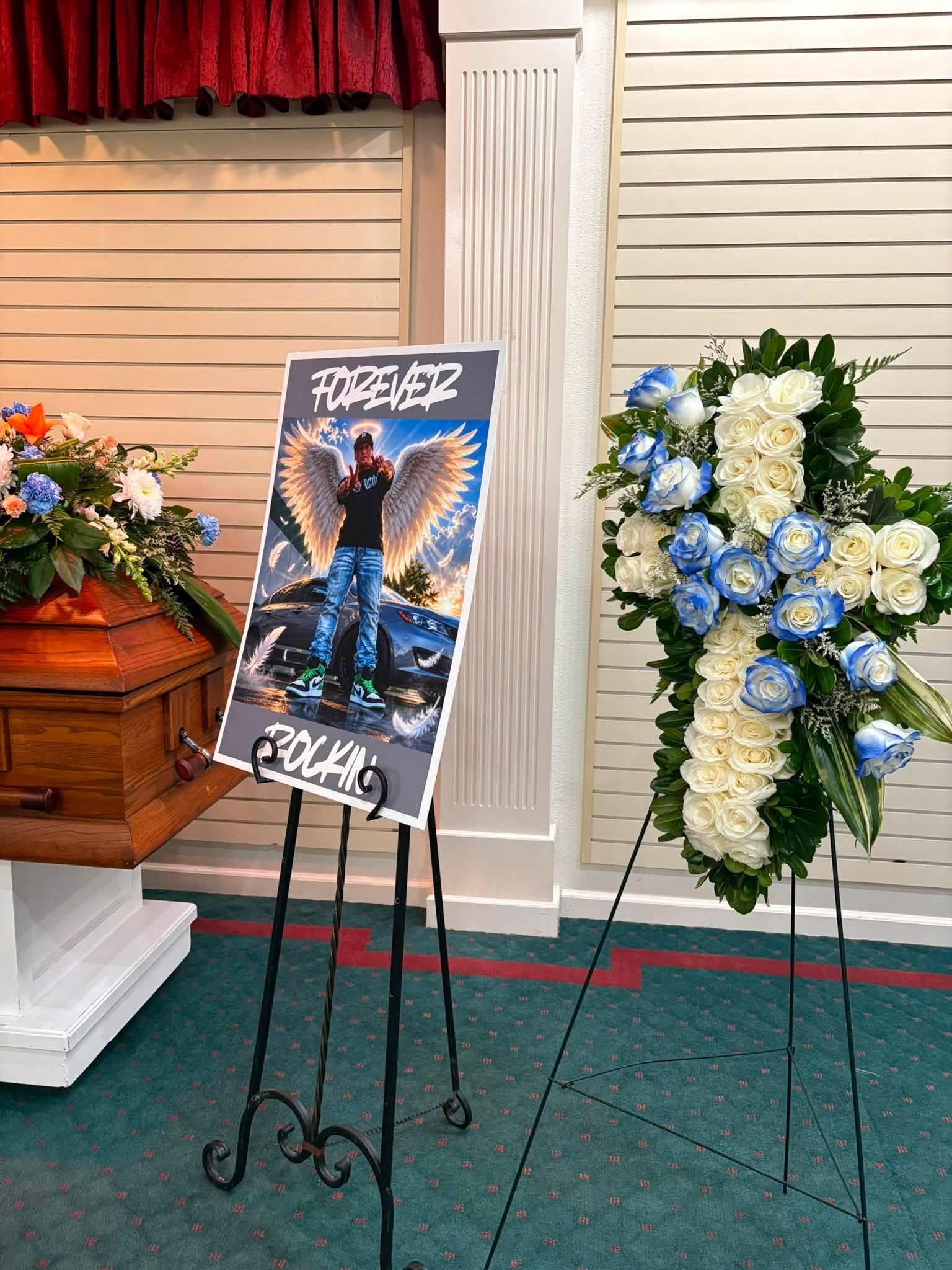 A poster and flowers in front of a coffin