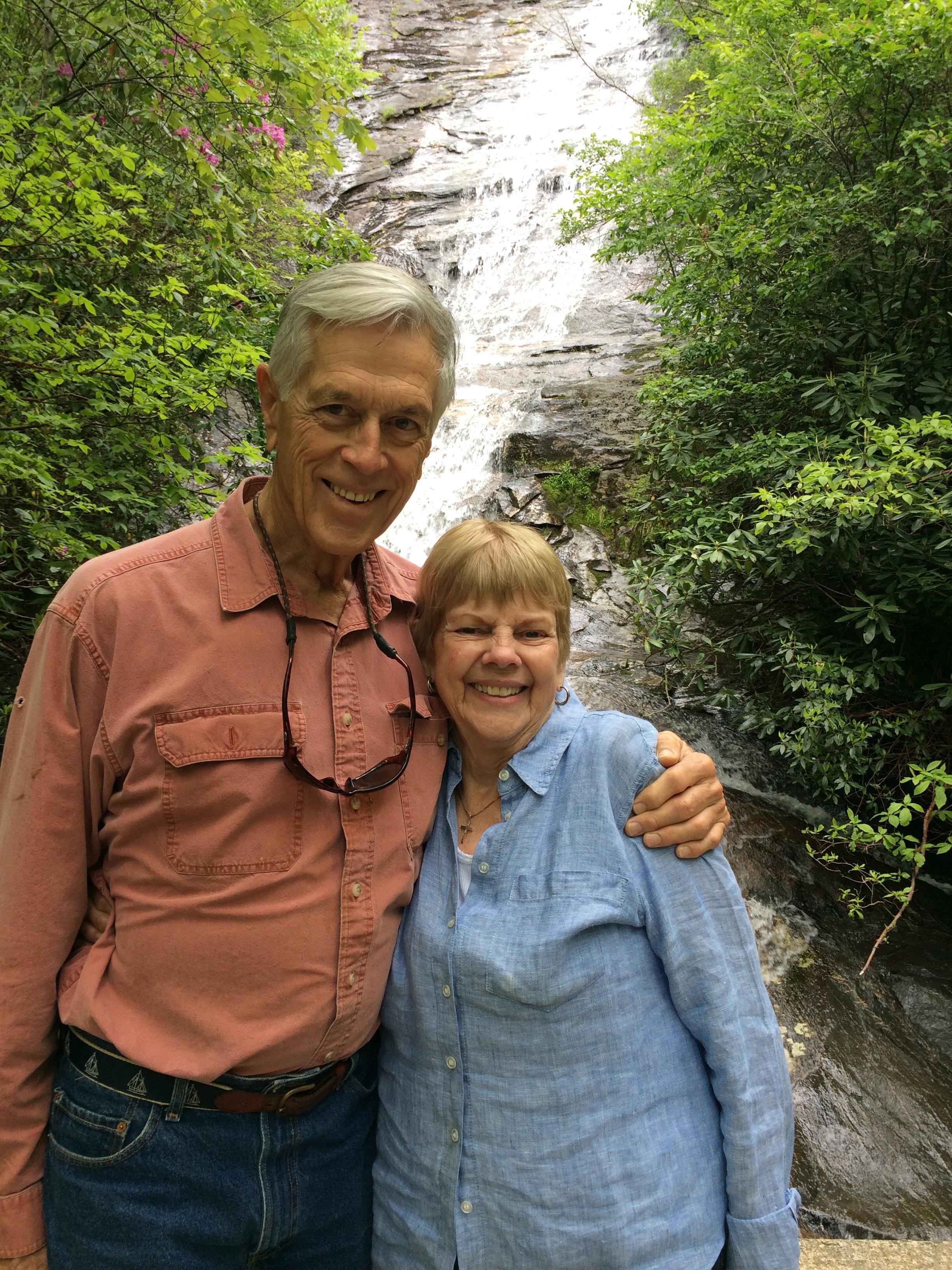 A man and woman standing in front of a waterfall