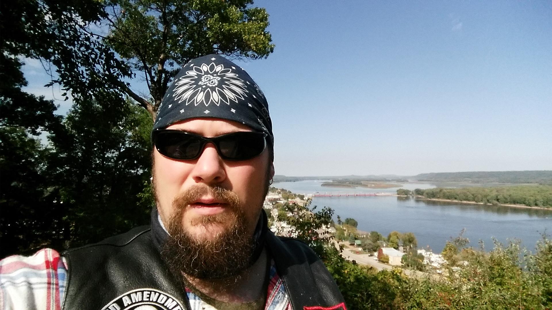 A man with a beard and sunglasses taking a selfie