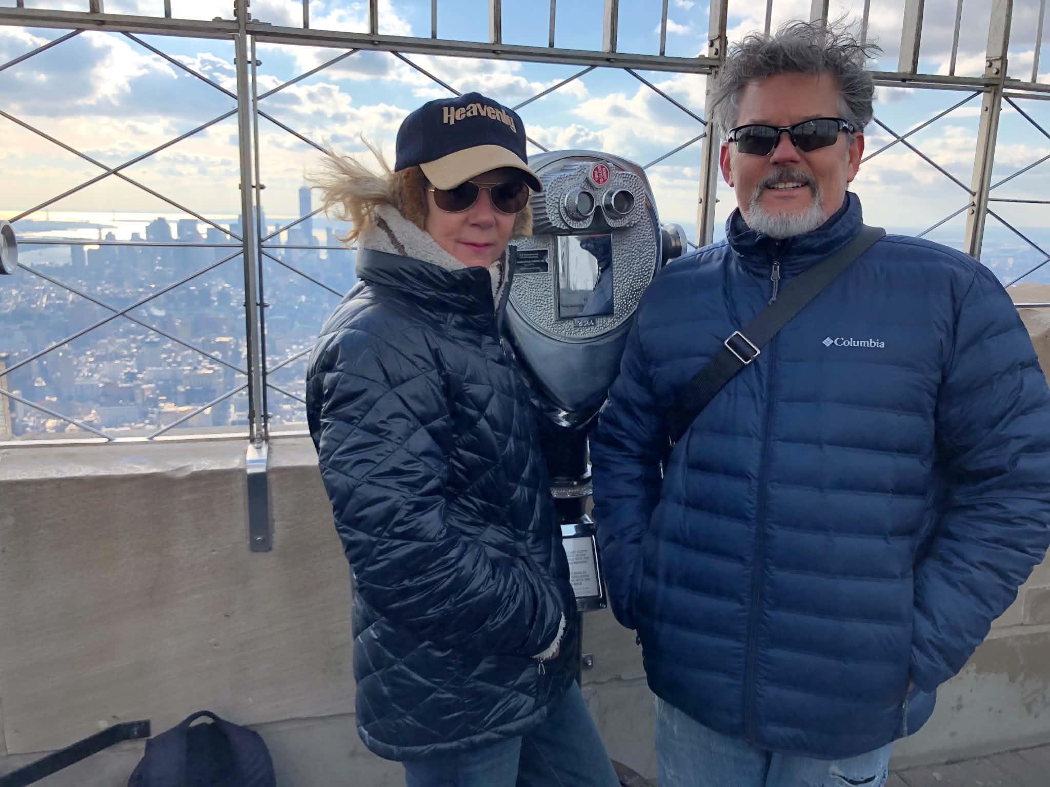 A man and woman standing in front of a telescope
