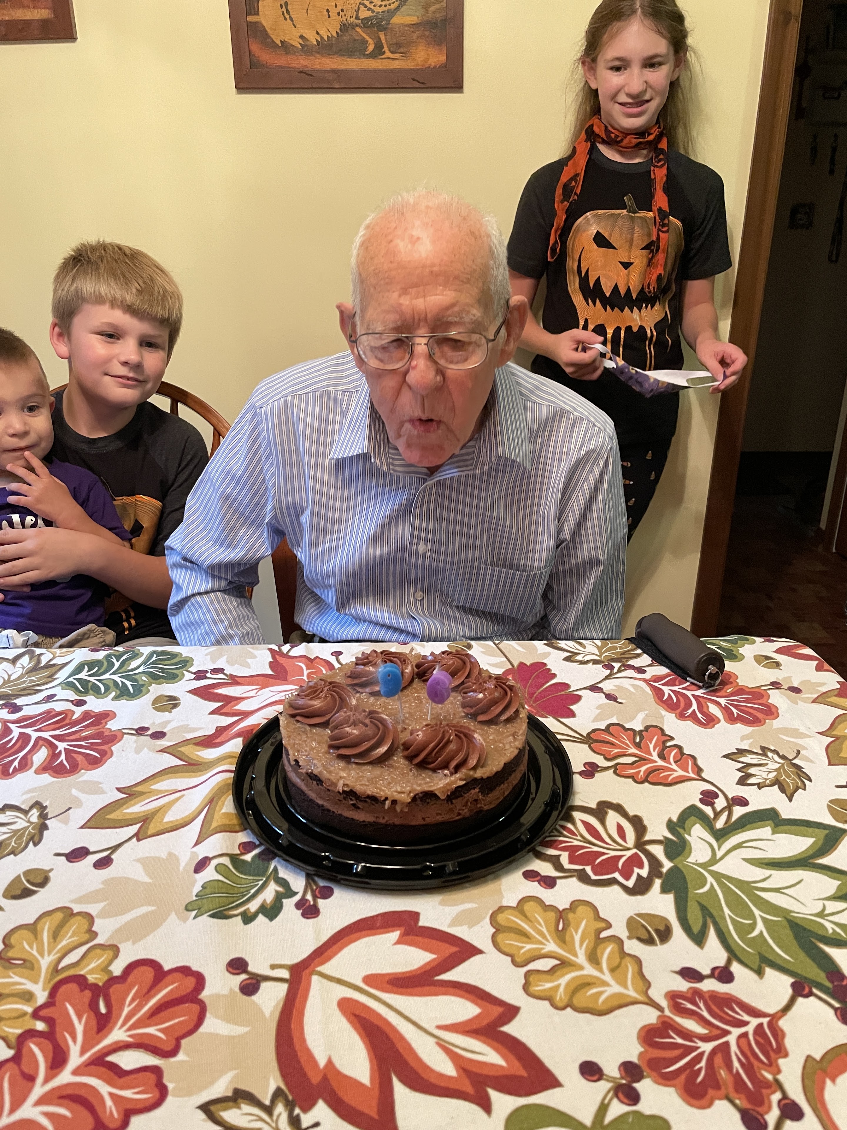 An old man sitting at a table with a cake