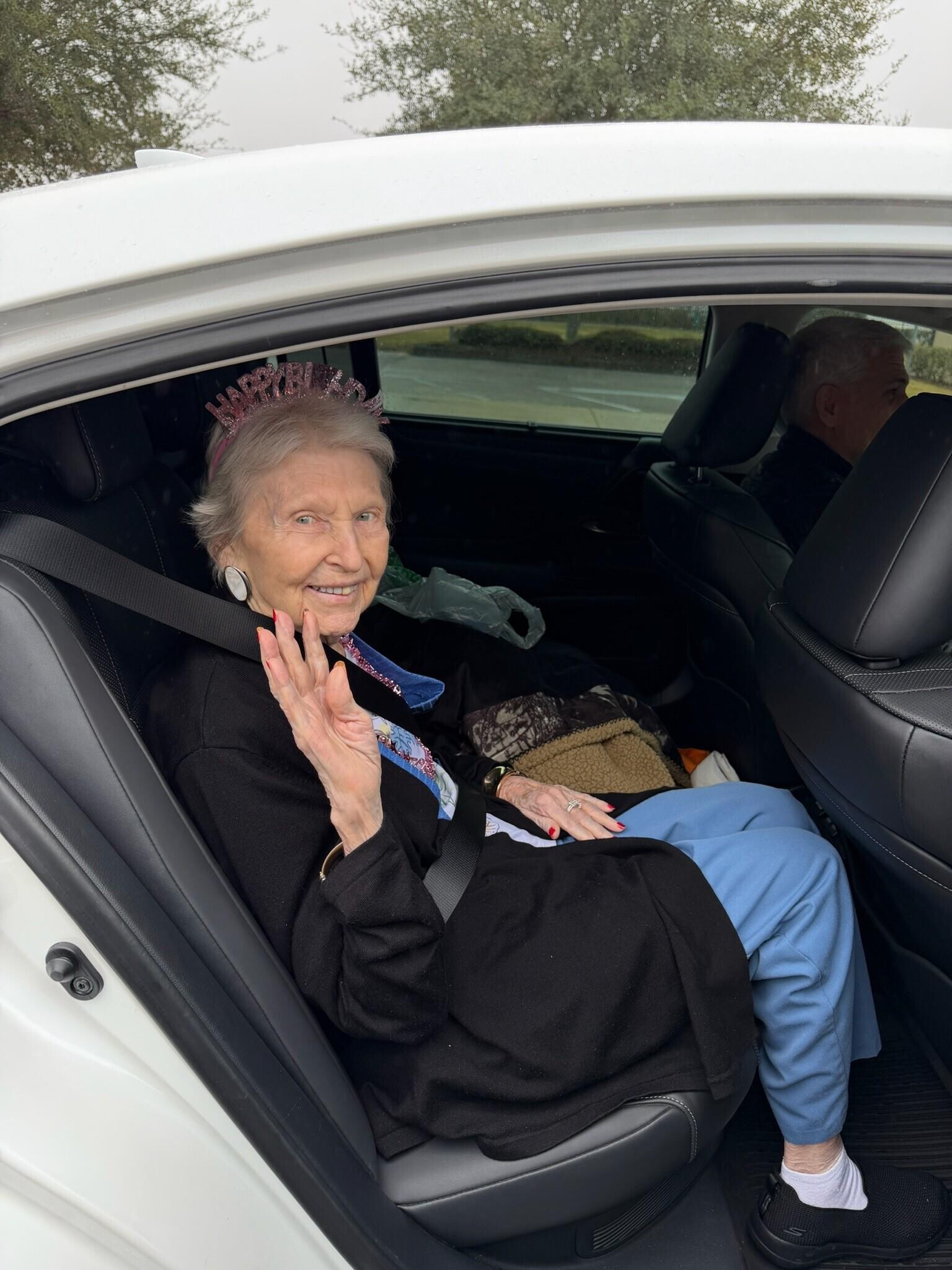An old woman in a car waving