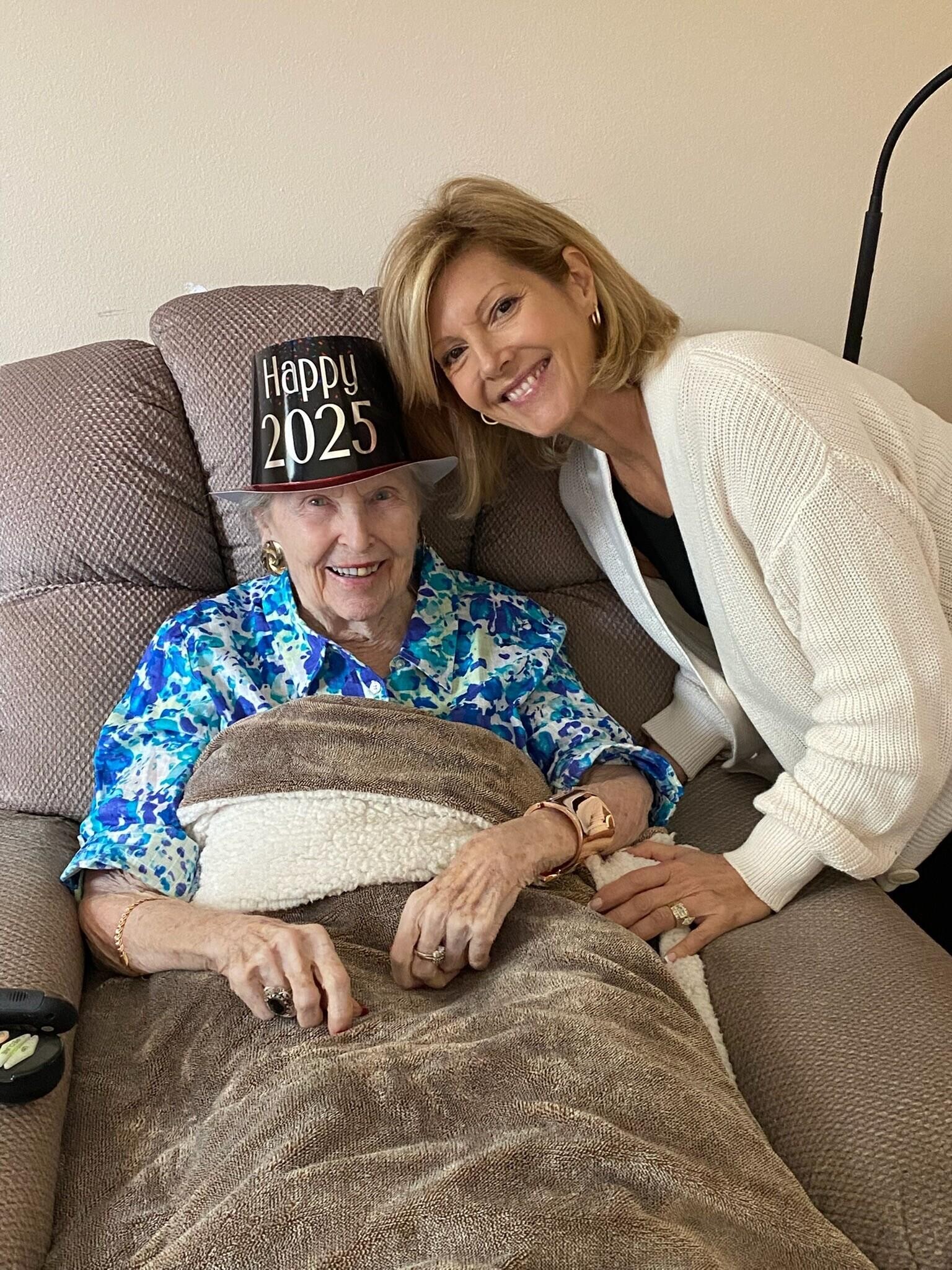 A woman smiling next to a woman lying on a couch