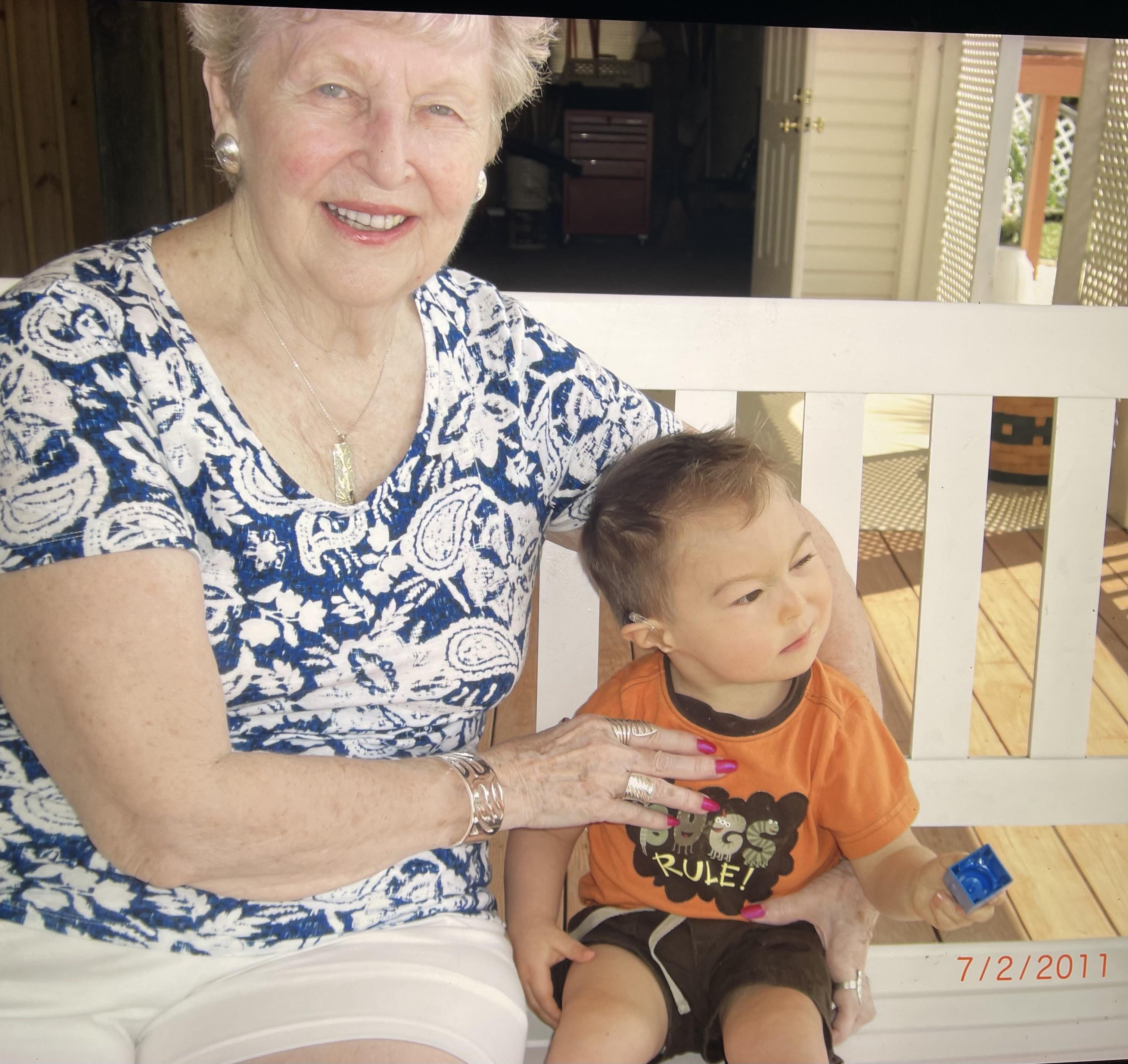 An old woman and a young boy sitting on a bench