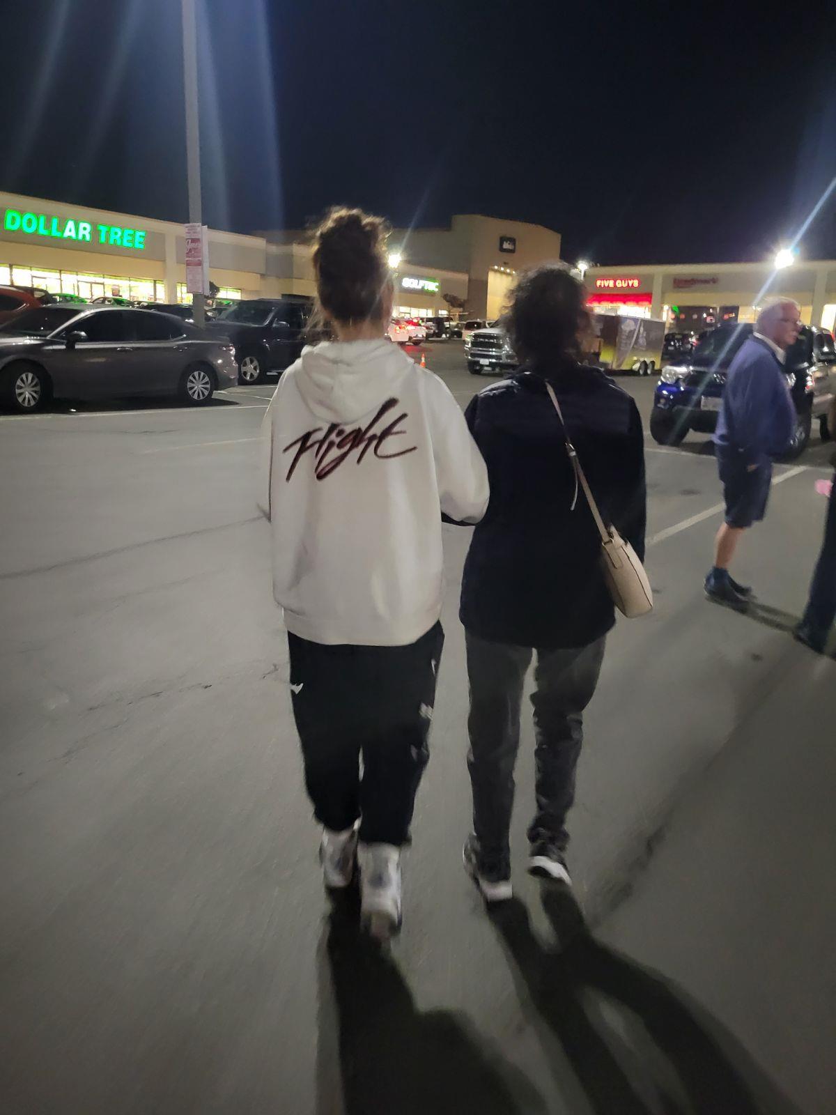 Two people walking on a parking lot