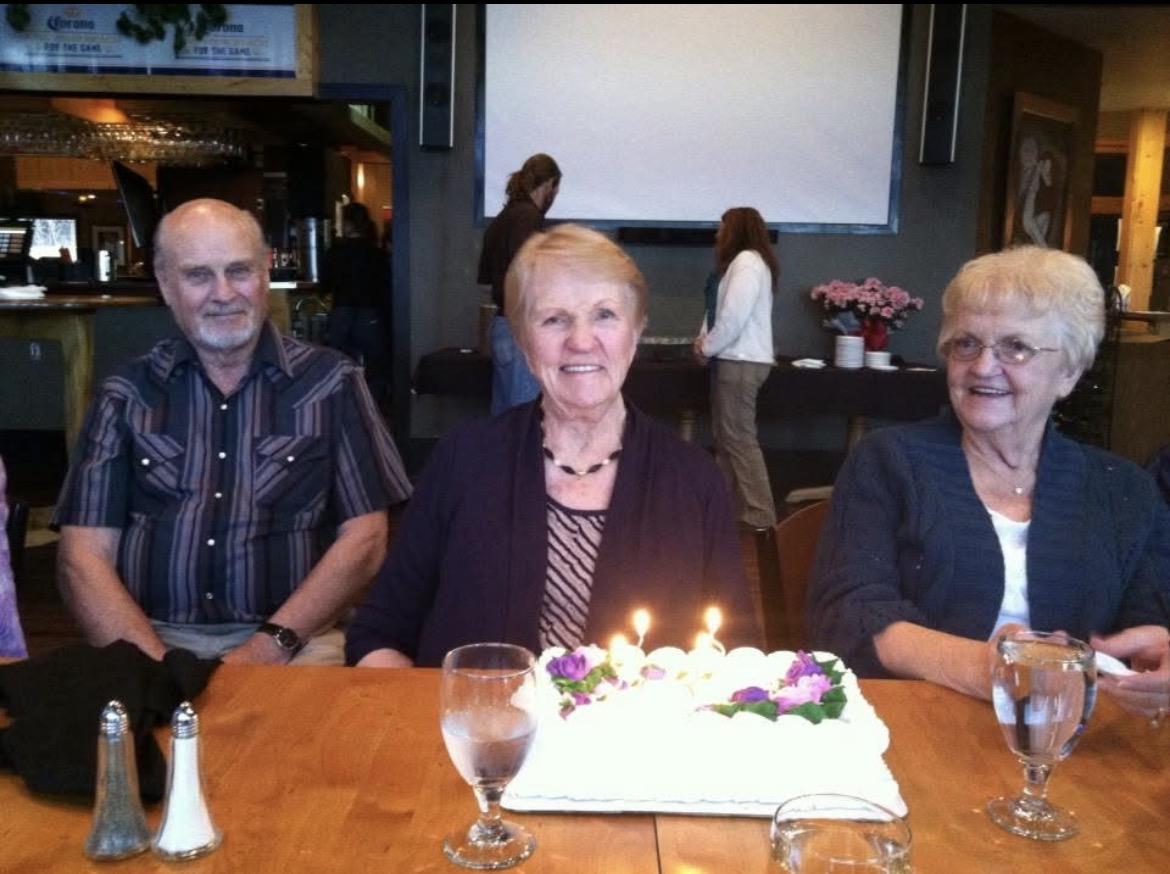 A group of people sitting at a table with a cake