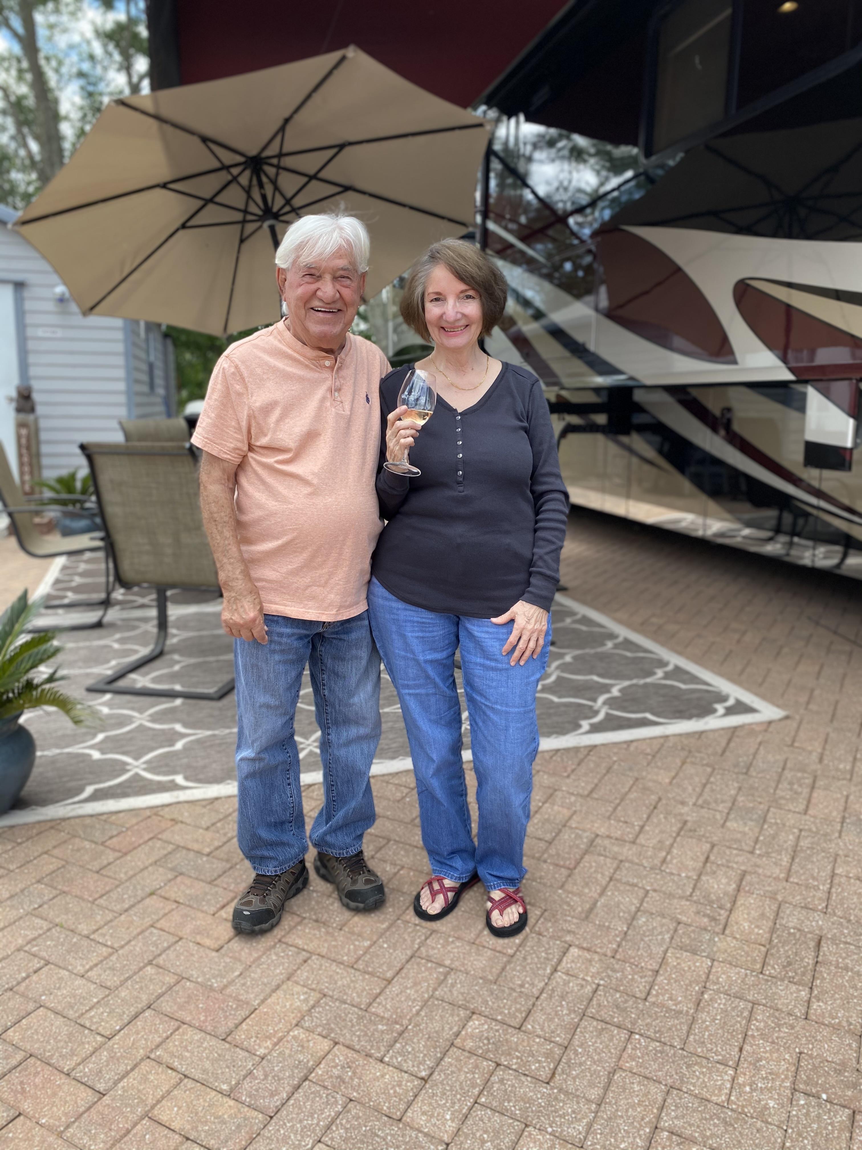 A man and woman standing on a brick patio with an umbrella