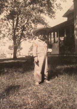 A man wearing a hat standing in front of a house