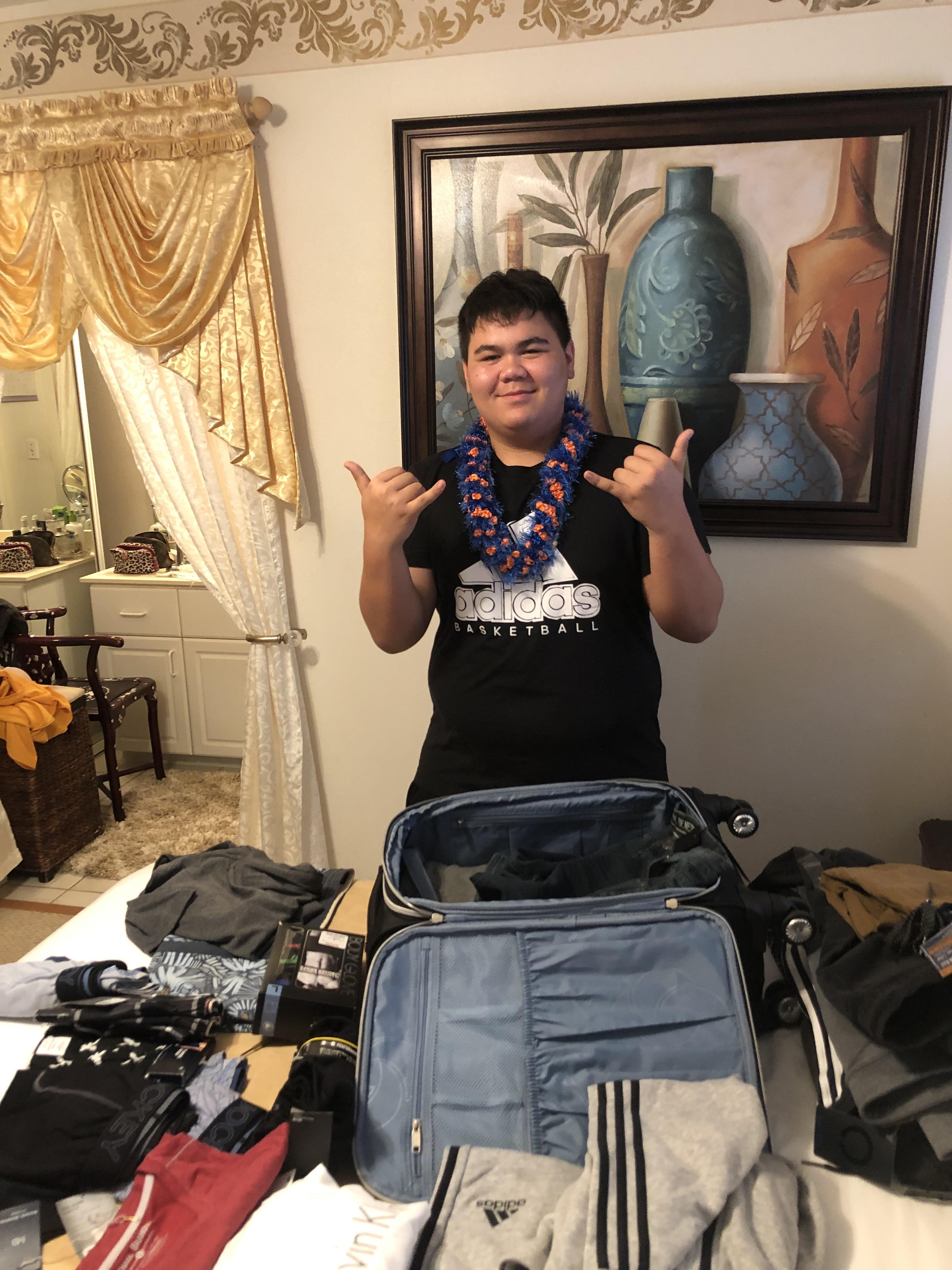A boy standing in front of a suitcase