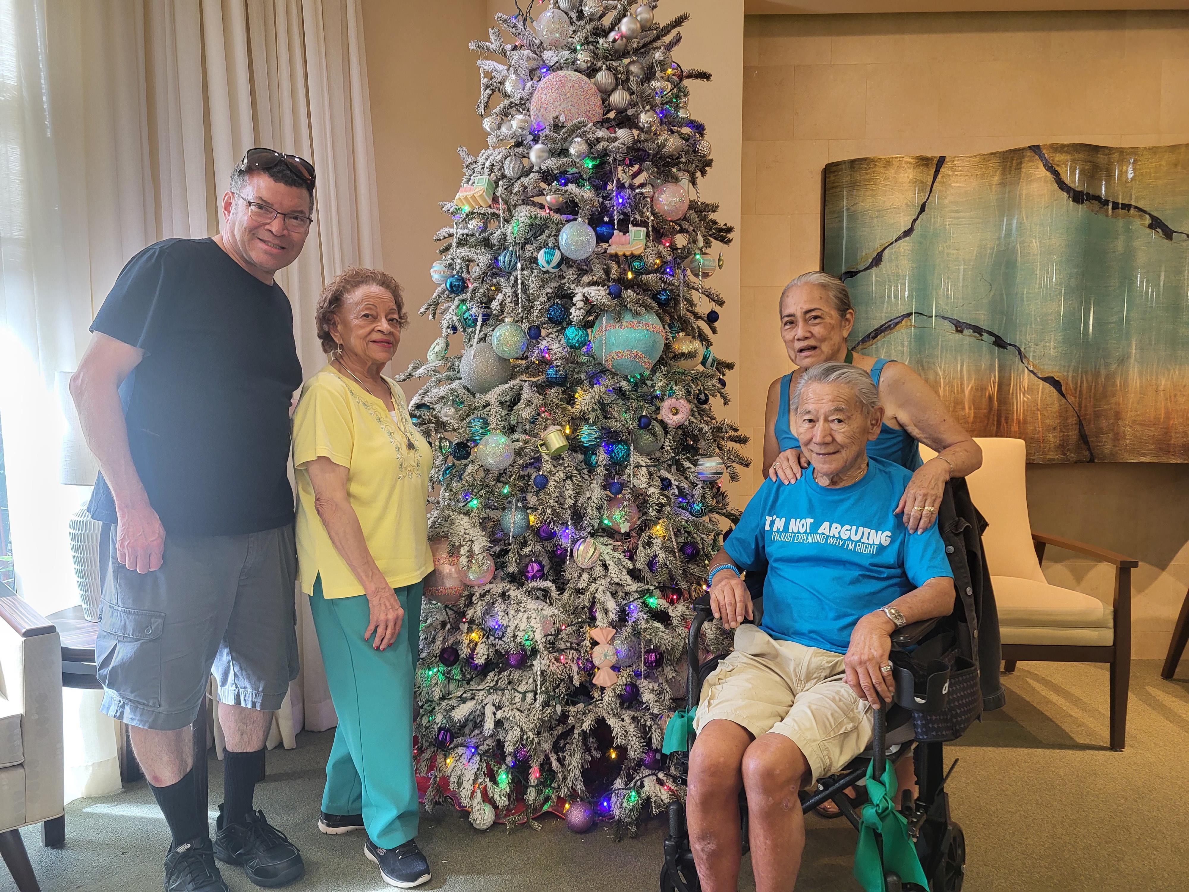 A group of people standing next to a christmas tree
