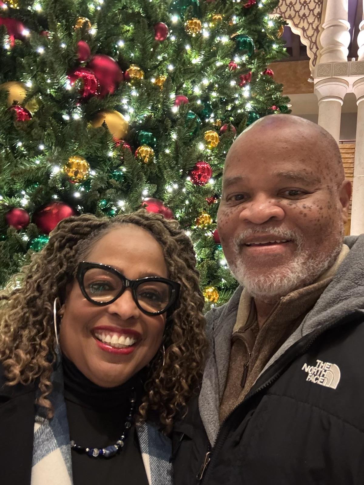 A man and woman standing in front of a christmas tree