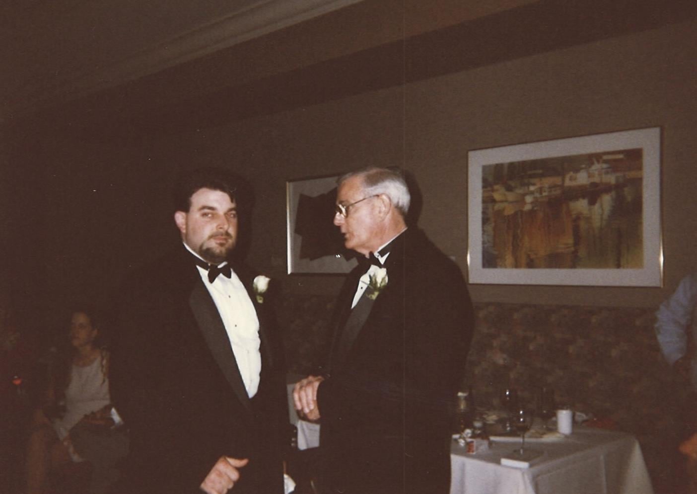 A man in tuxedo talking to another man