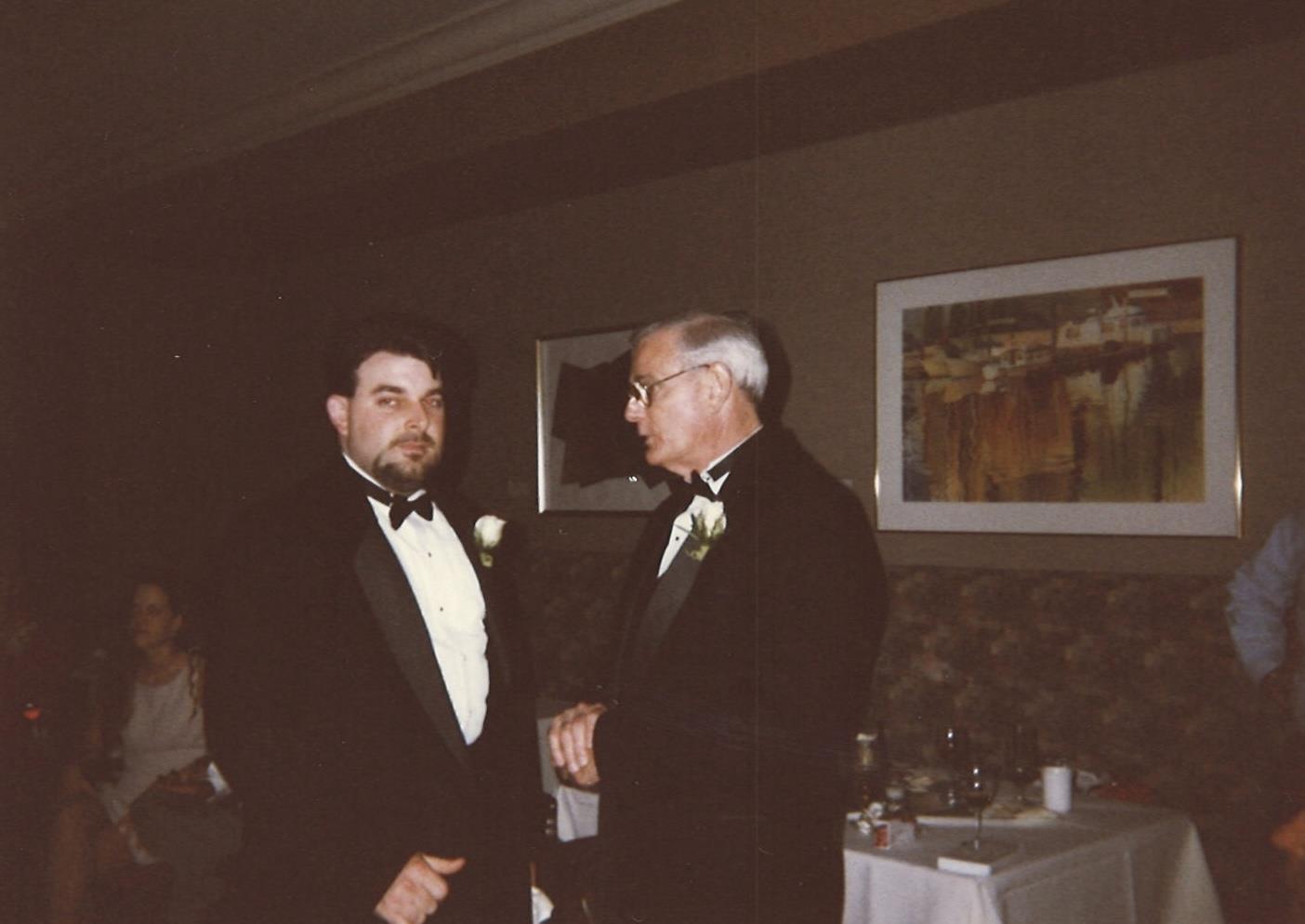 A man in tuxedo talking to another man