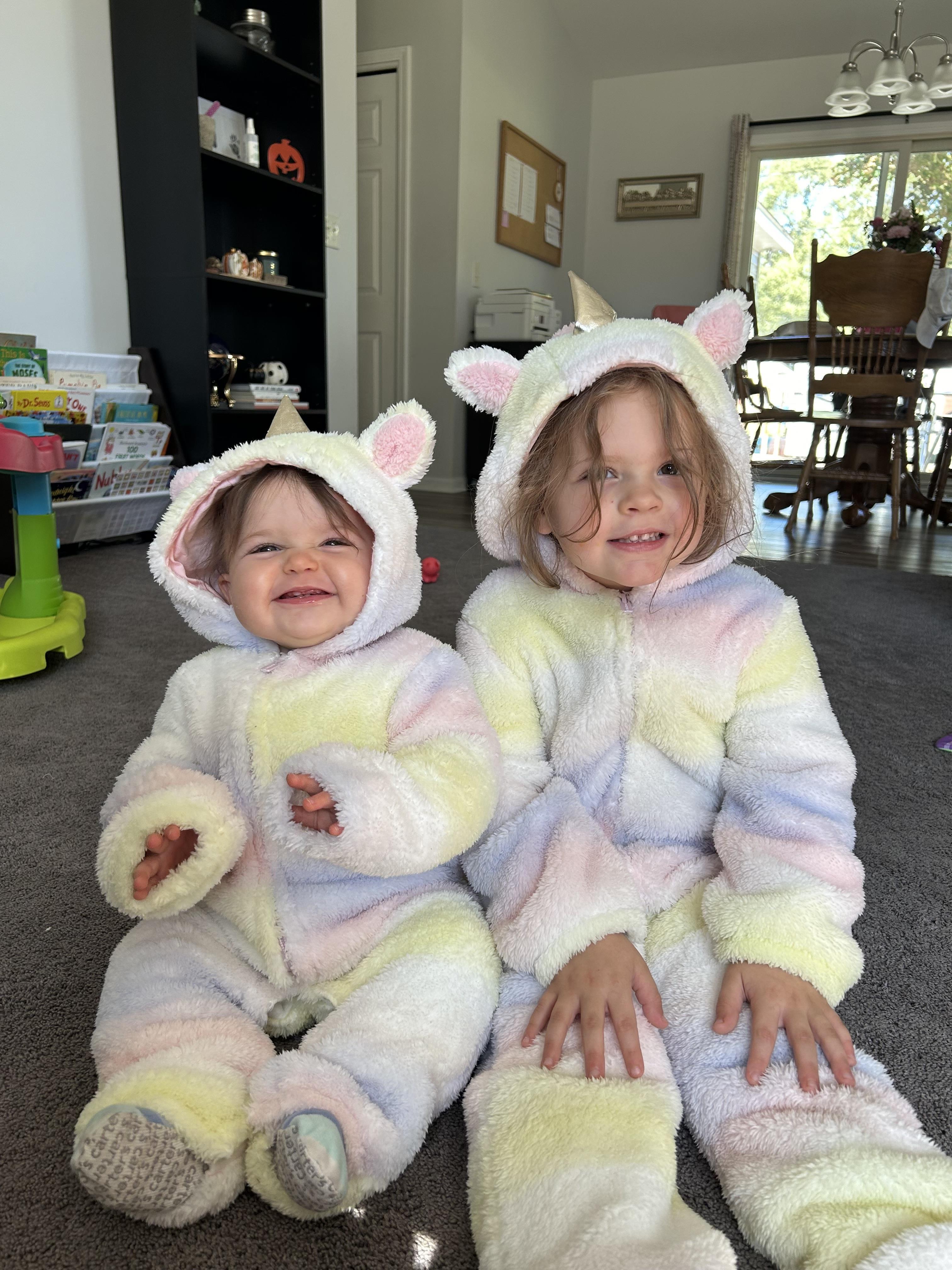 Two children wearing clothing sitting on the floor