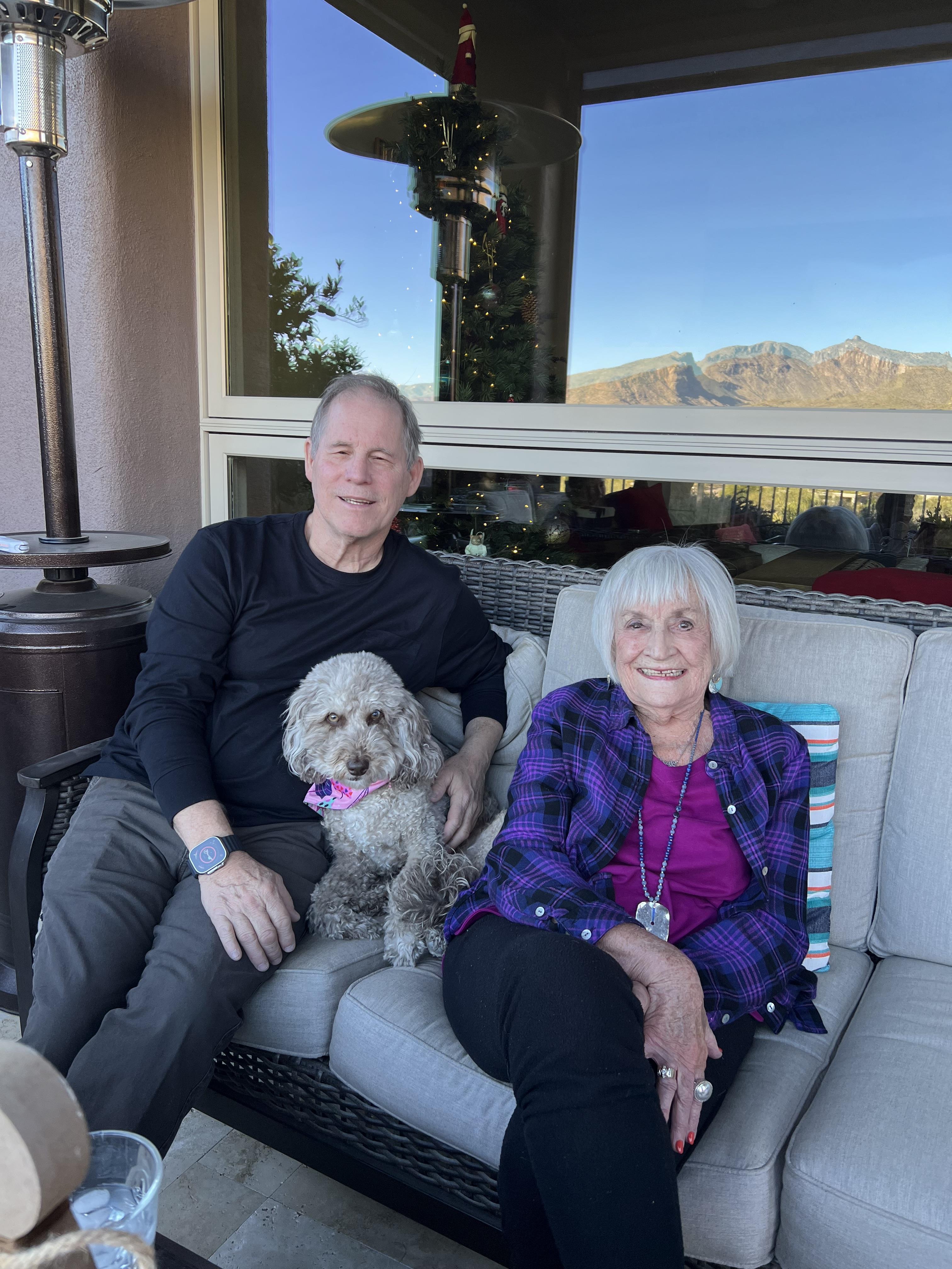A man and woman sitting on a couch with a dog