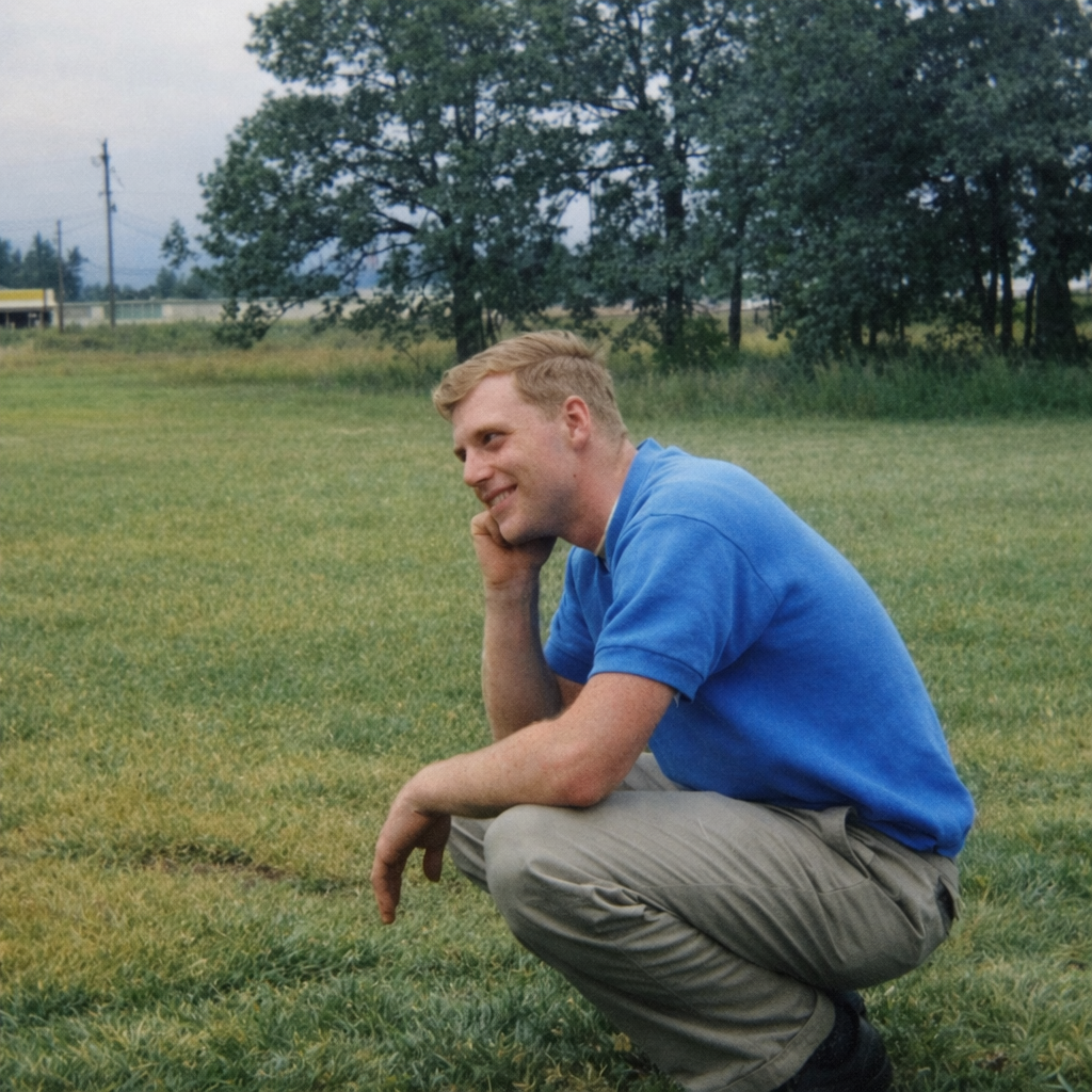 A man squatting in a field