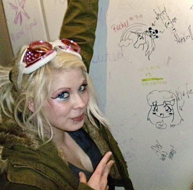 A woman with her arms up and a white board with writing on it