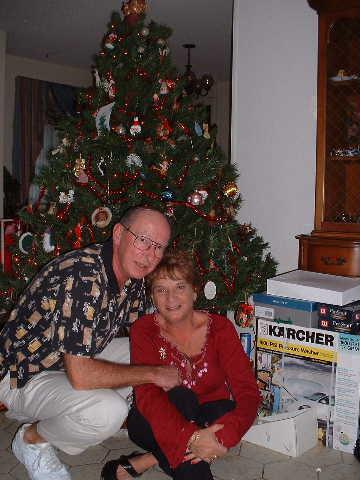A man and woman sitting on a couch in front of a christmas tree