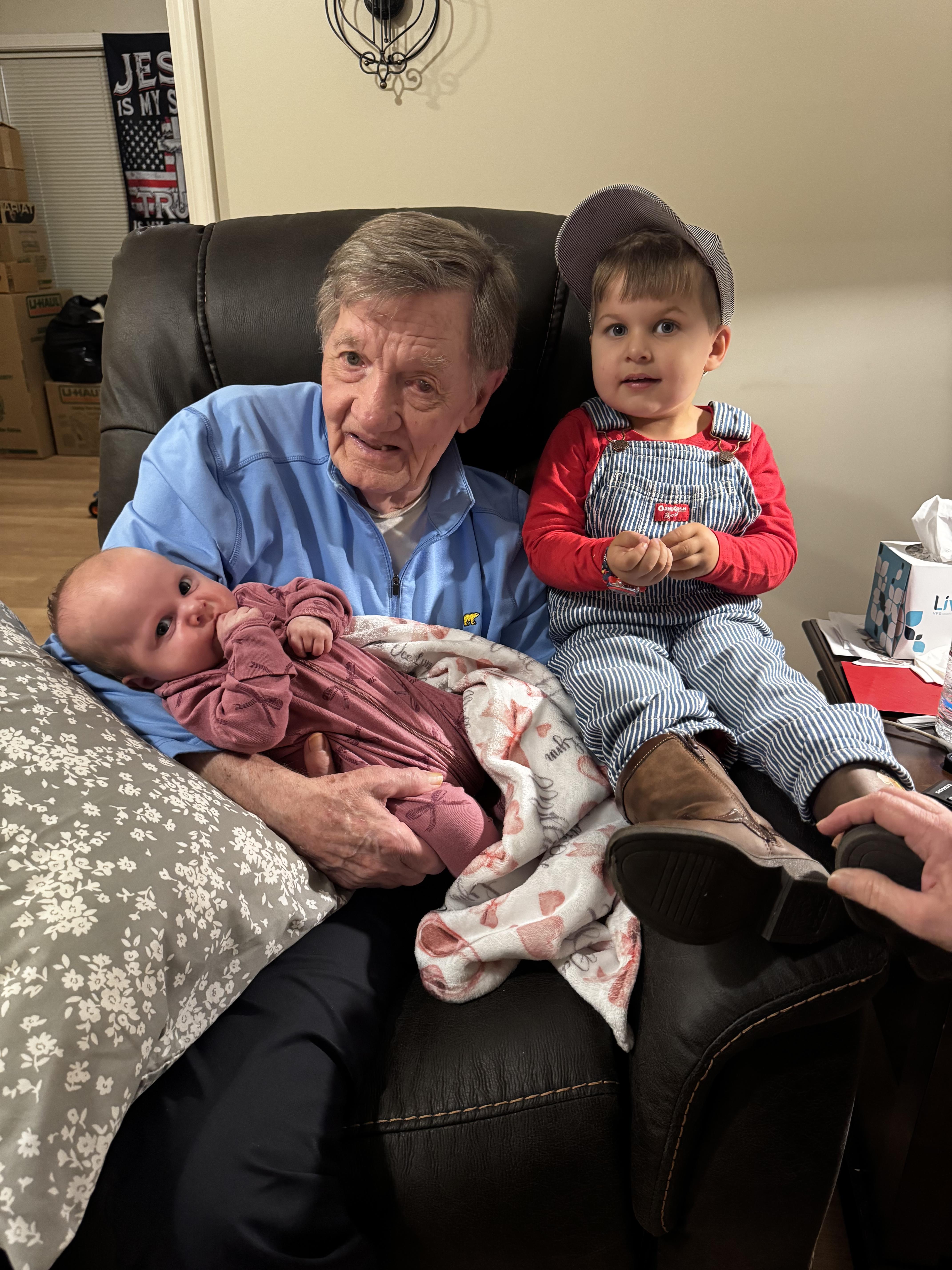 An older man sitting on a couch with a baby and a baby