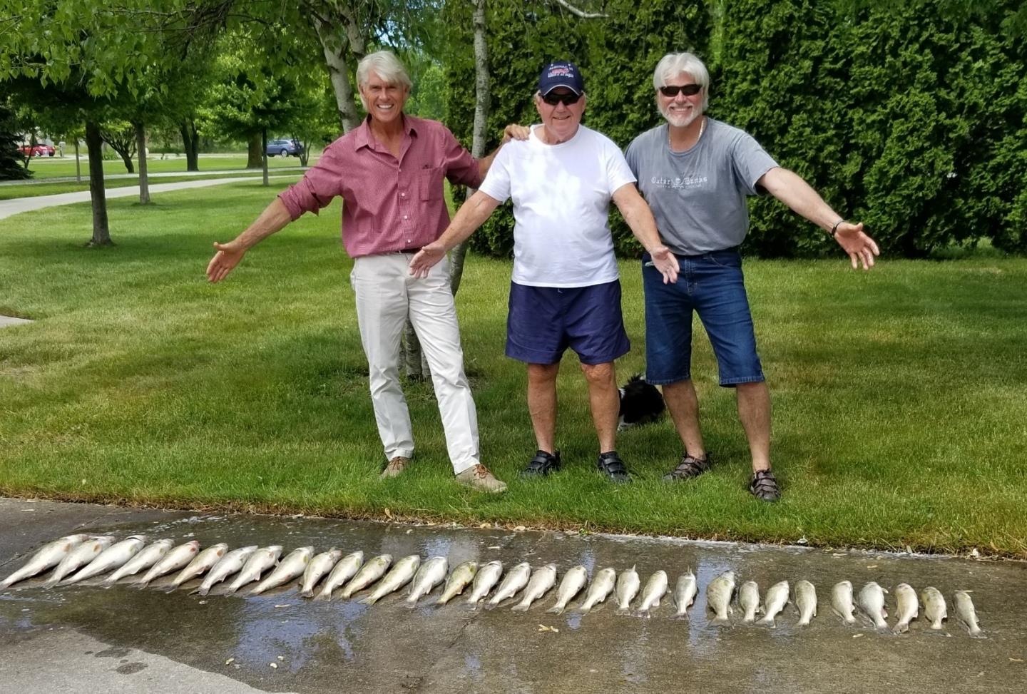 A group of men standing in front of a row of fish