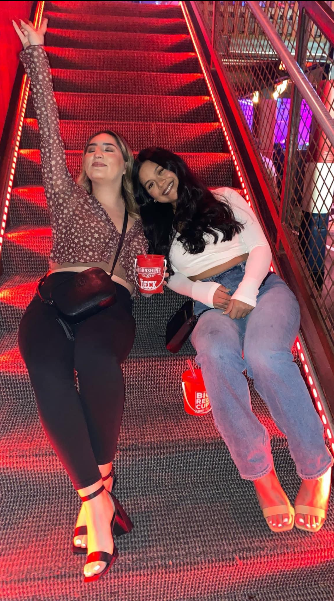 Two women sitting on stairs with red lights