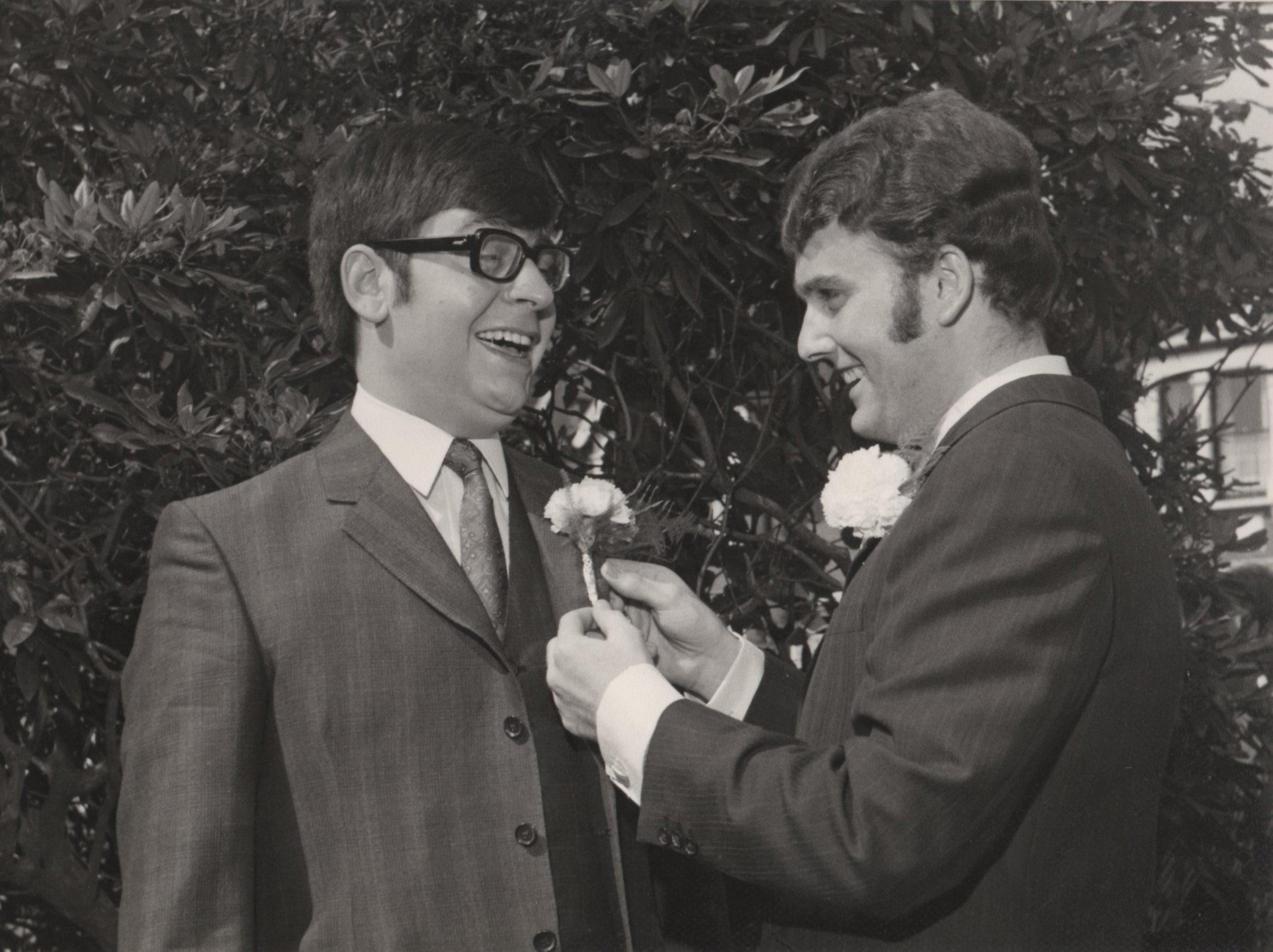 A man holding a flower to another man